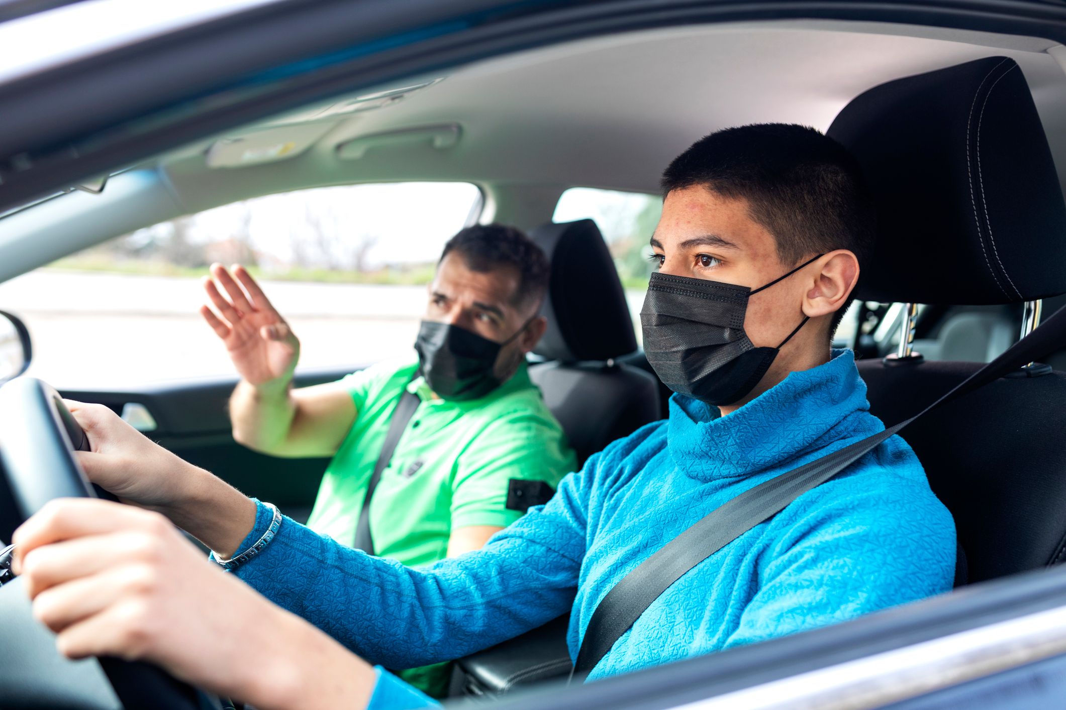 Teenage boy having driving lesson with male instructor during  Covid  19 pandemic