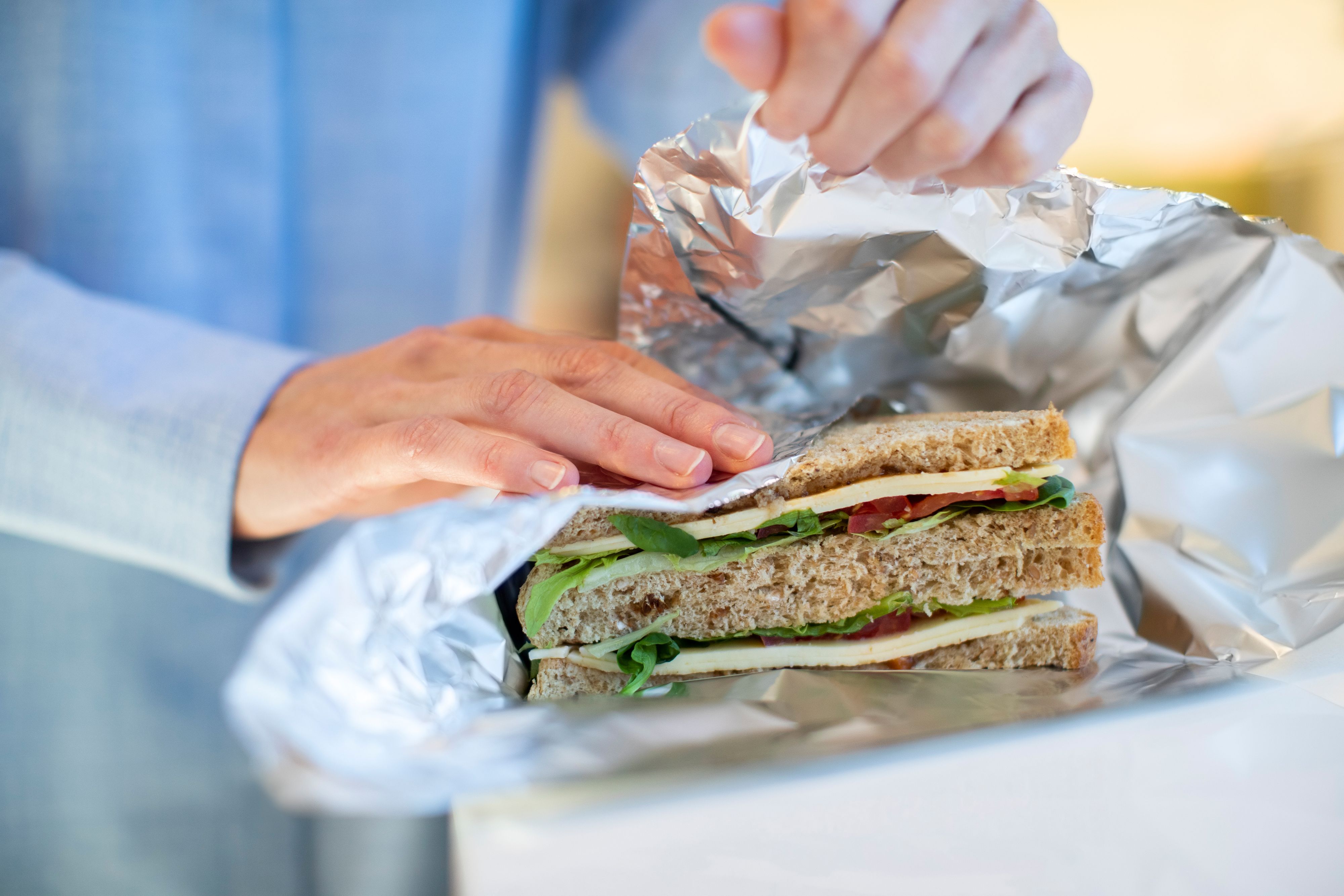 Close Up Of Woman Wrapping Sandwich In Non Reusable Aluminium Foil
