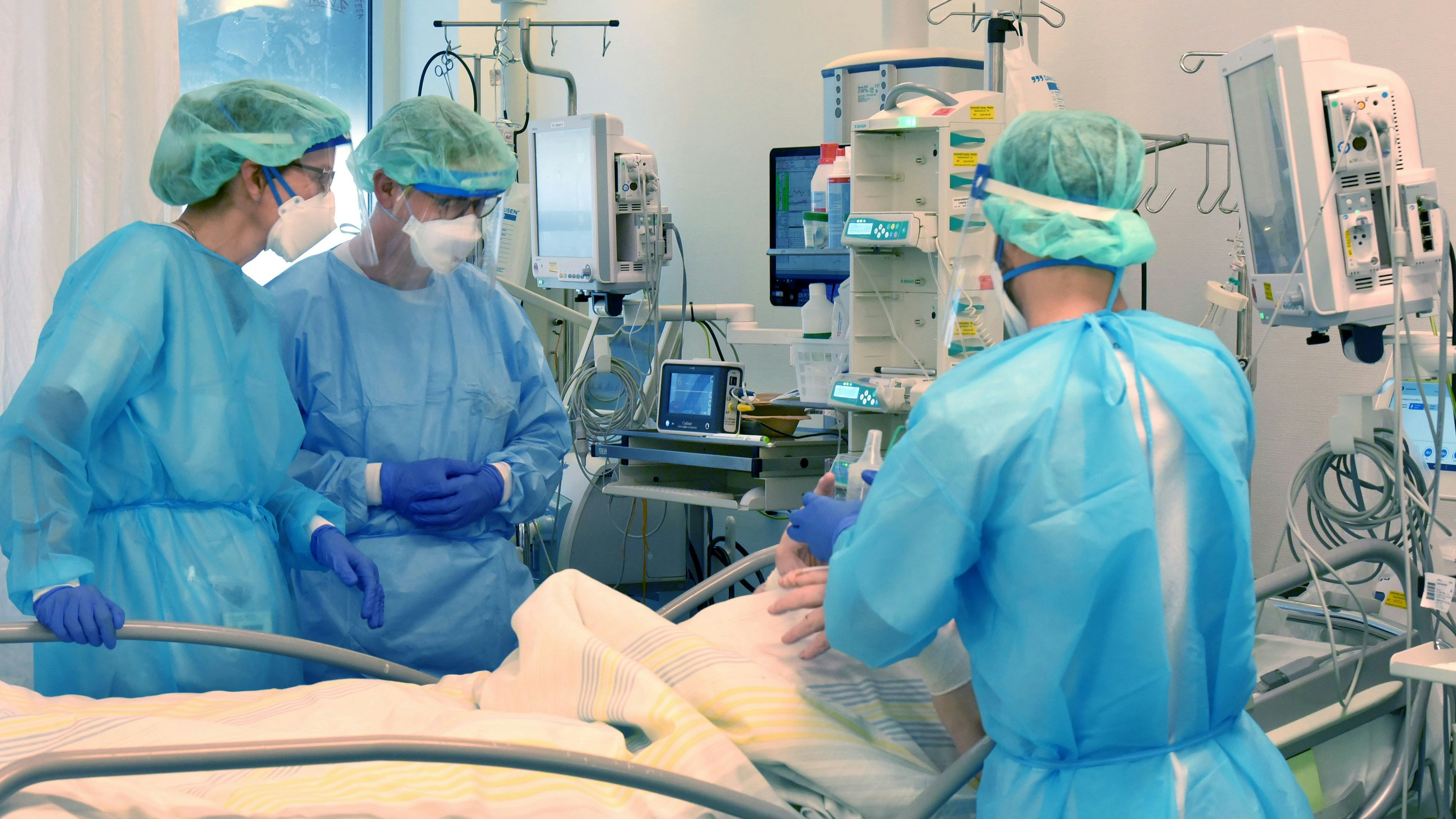 Download von www.picturedesk.com am 25.11.2021 (09:13).  08 November 2021, Saxony, Leipzig: In the Covid ward, an area of the Operative Intensive Care Unit of Leipzig University Hospital, the head of the clinic, Prof. Dr. Sebastian Stehr (centre) with the head of the department, Sylvia Köppen (left), and a nurse stand at the bedside of a seriously ill patient. In the intensive care unit, the number of corona patients with severe courses has been growing for days, including more and more younger patients between 30 and 60 years of age. Photo: Waltraud Grubitzsch/dpa-Zentralbild/ZB - 20211108_PD13031 - Rechteinfo: Rights Managed (RM)