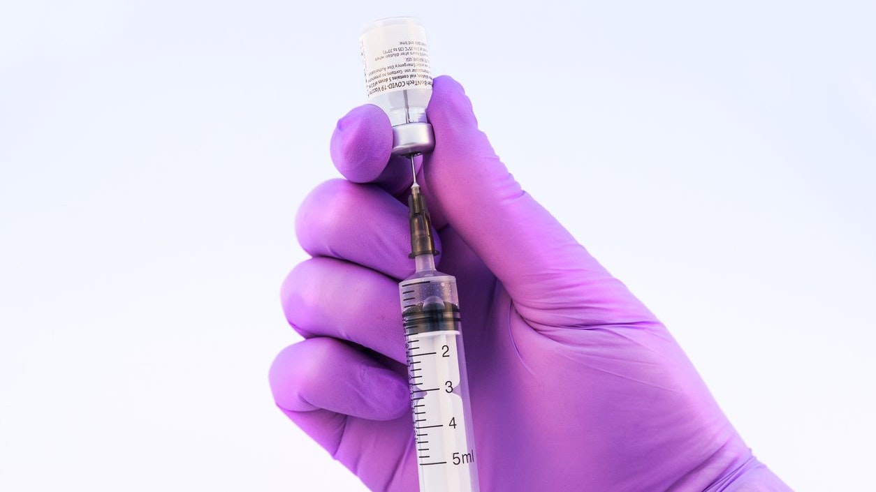 Brasov, Romania - February 21, 2021: Doctor using Pfizer-BioNTech Covid-19 vaccine on a white background.