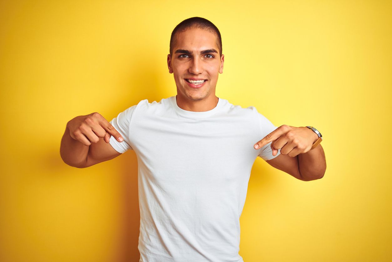 Young caucasian man wearing casual white t-shirt over yellow isolated background looking confident with smile on face, pointing oneself with fingers proud and happy.