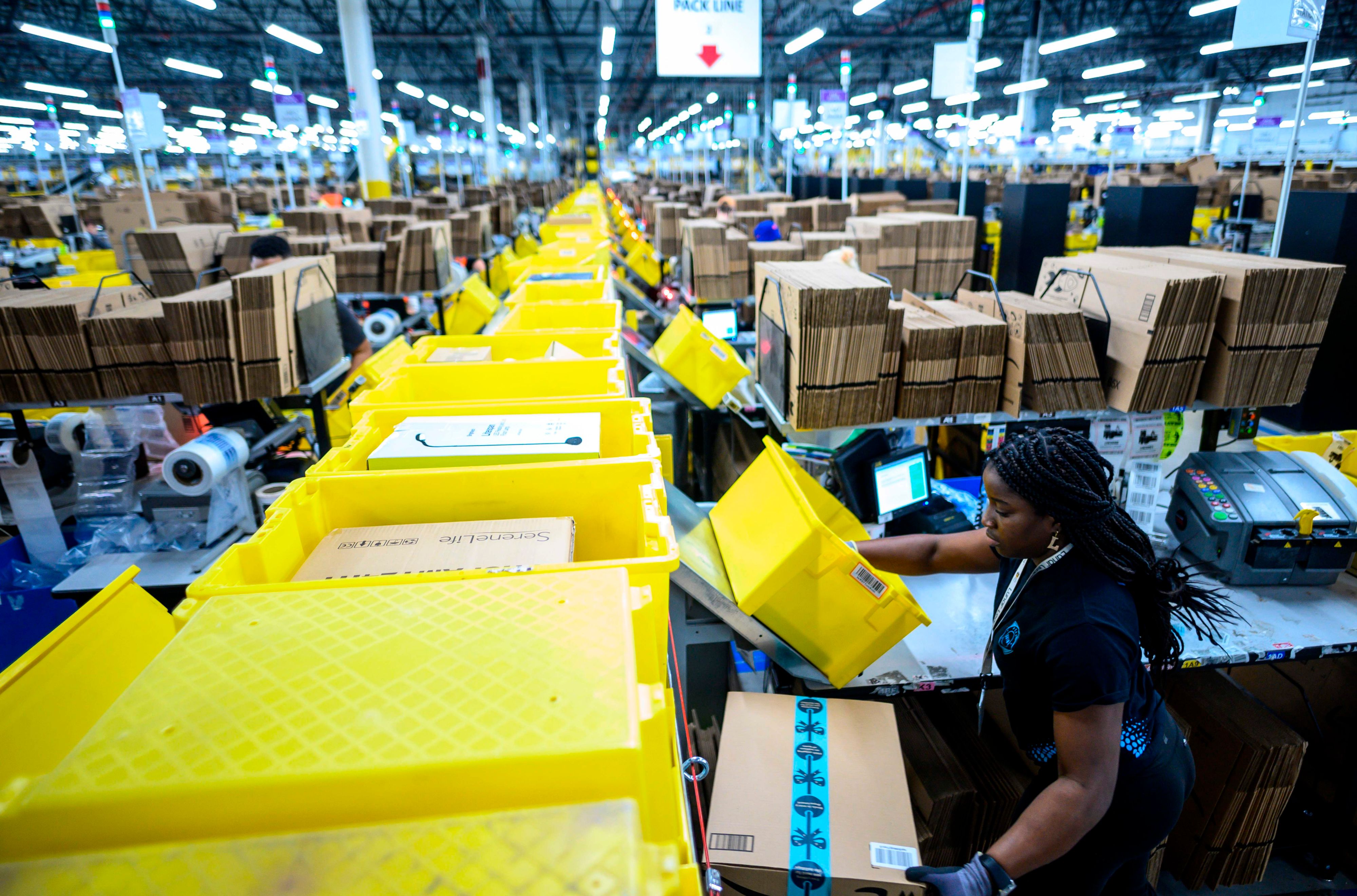 Download von www.picturedesk.com am 09.12.2021 (10:52).  (FILES) In this file photo taken on February 5, 2019 a woman works at a packing station at the 855,000-square-foot Amazon fulfillment center in Staten Island, one of the five boroughs of New York City. - Hundreds of Amazon employees on January 26, 2020 openly criticized the online retail giant's environmental record, in violation of the company's communications policy. More than 300 signed a Medium blog post by Amazon Employees for Climate Justice (AECJ), which is pushing the company to go further in its climate change mitigation plan which was announced with great publicity in September. (Photo by Johannes EISELE / AFP) - 20190205_PD19005 - Rechteinfo: Rights Managed (RM) Nur für redaktionelle Nutzung! Werbliche Nutzung erfordert Freigabe: bitte schicken Sie uns eine Anfrage.