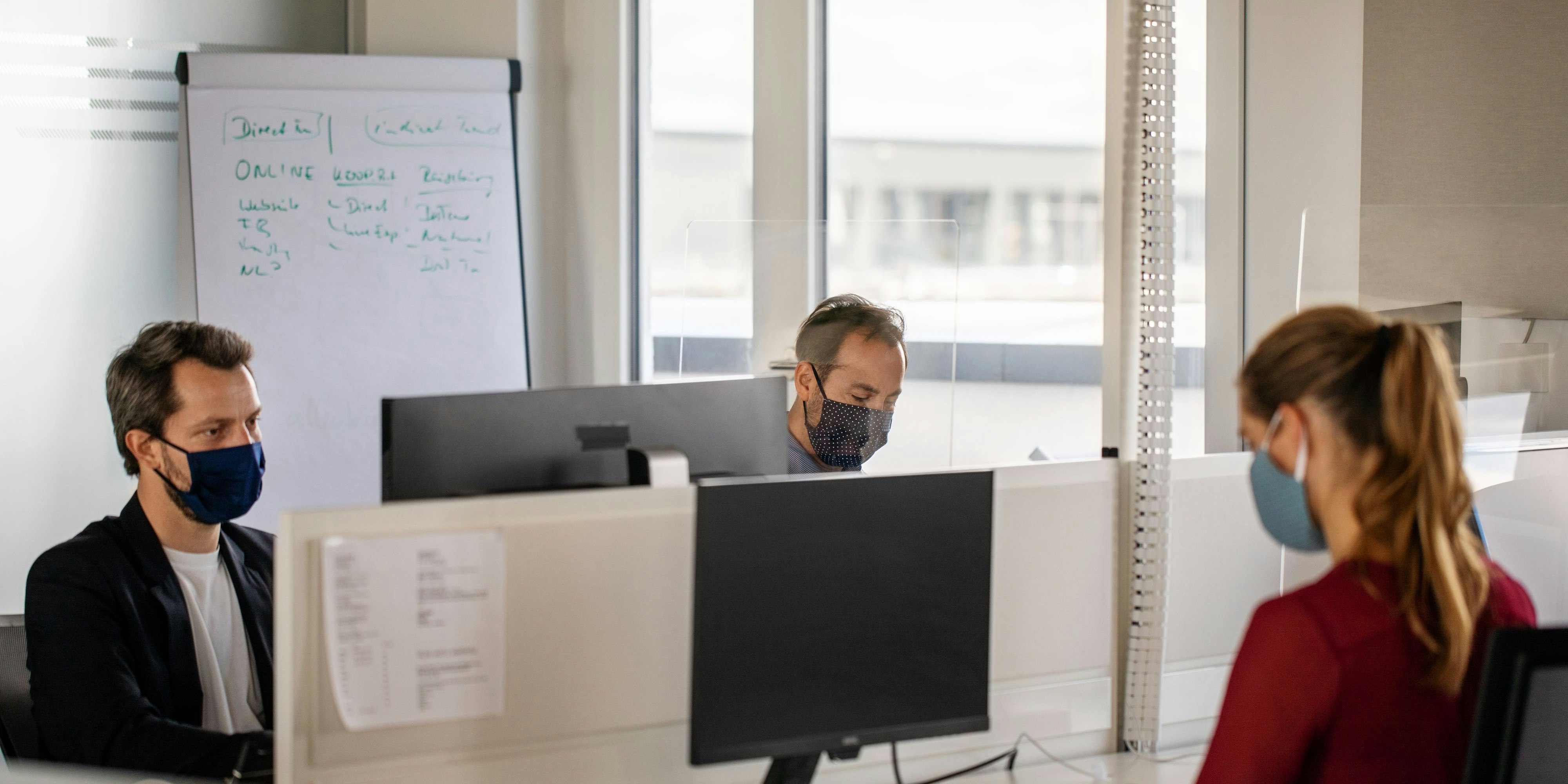 Business people wearing protective face masks working in a coworking office. Colleagues working in office during covid-19 pandemic.
