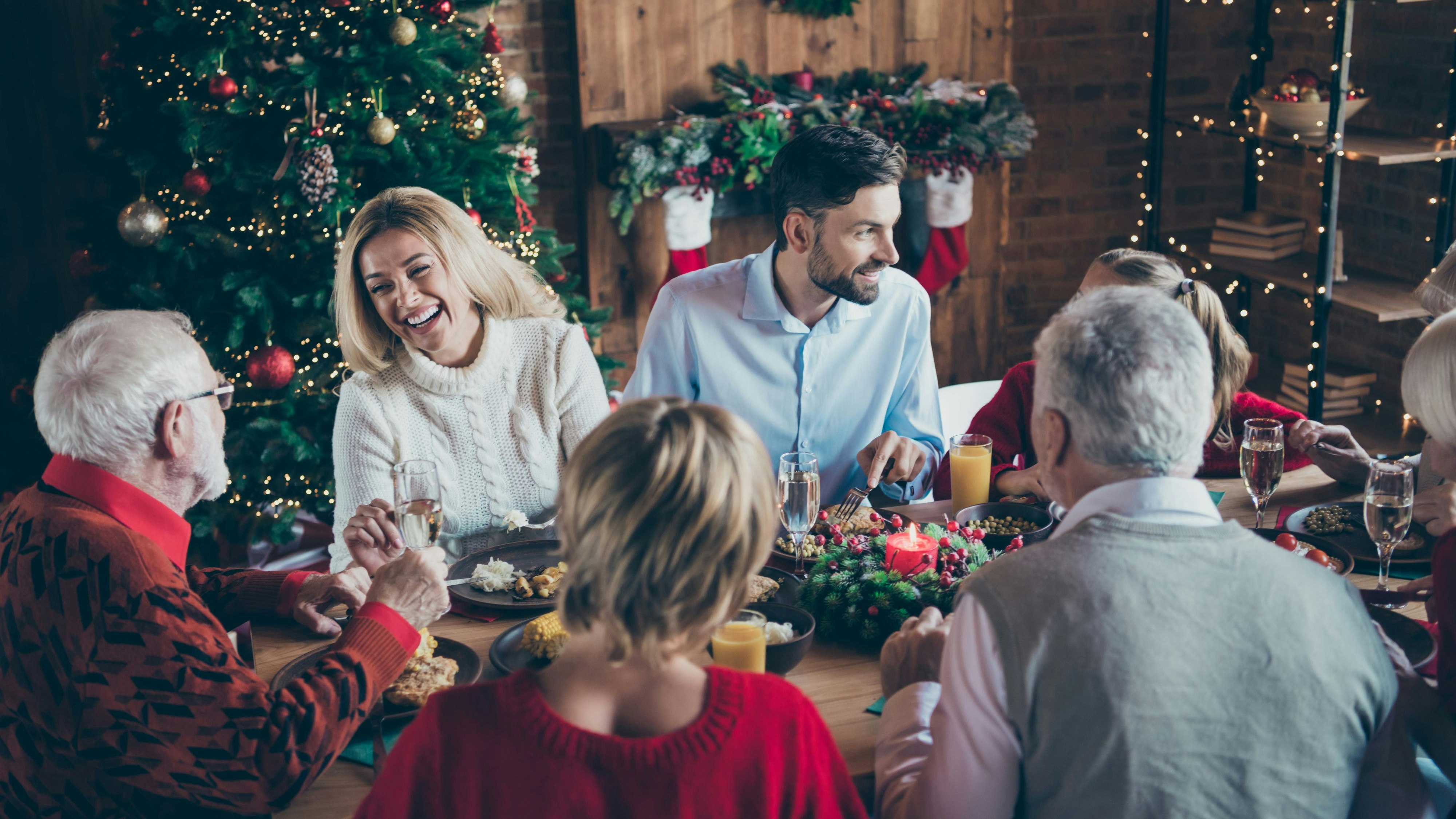 Photo of full family gathering sitting dinner table communicating chatting overjoyed x-mas party multi-generation in newyear decorated living room indoors