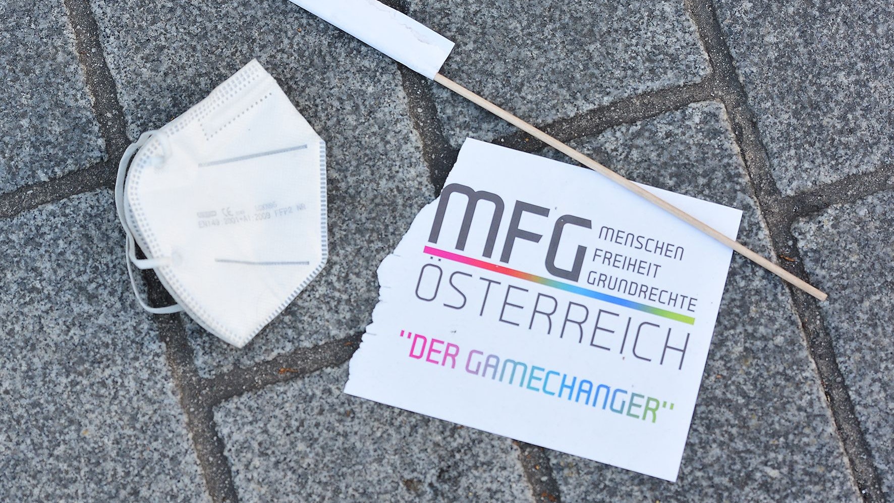 Download von www.picturedesk.com am 17.12.2021 (13:33).  21.11.2021, AUT, Linz, Reportage, Fototermin, , die österreichische impfkritische Kleinpartei MFG ruft am 21.11.2021 zur Kundgebung vor dem Linzer Landhaus auf. .im Bild FFP2 Maske am Boden mit einer zerstörten Fahne der MFG Partei PhotoCredit Johanna Schlosser - 20211121_PD20738 - Rechteinfo: Rights Managed (RM)