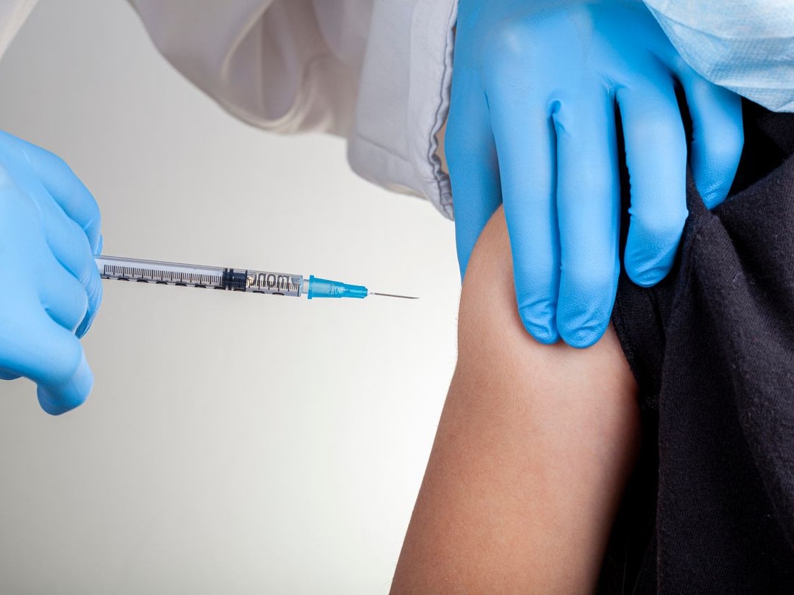 A health care professional wearing gloves and white coat is administering a childhood vaccine to a caucasian kid. Closeup Concept image for child vaccination, immunization clinical trial