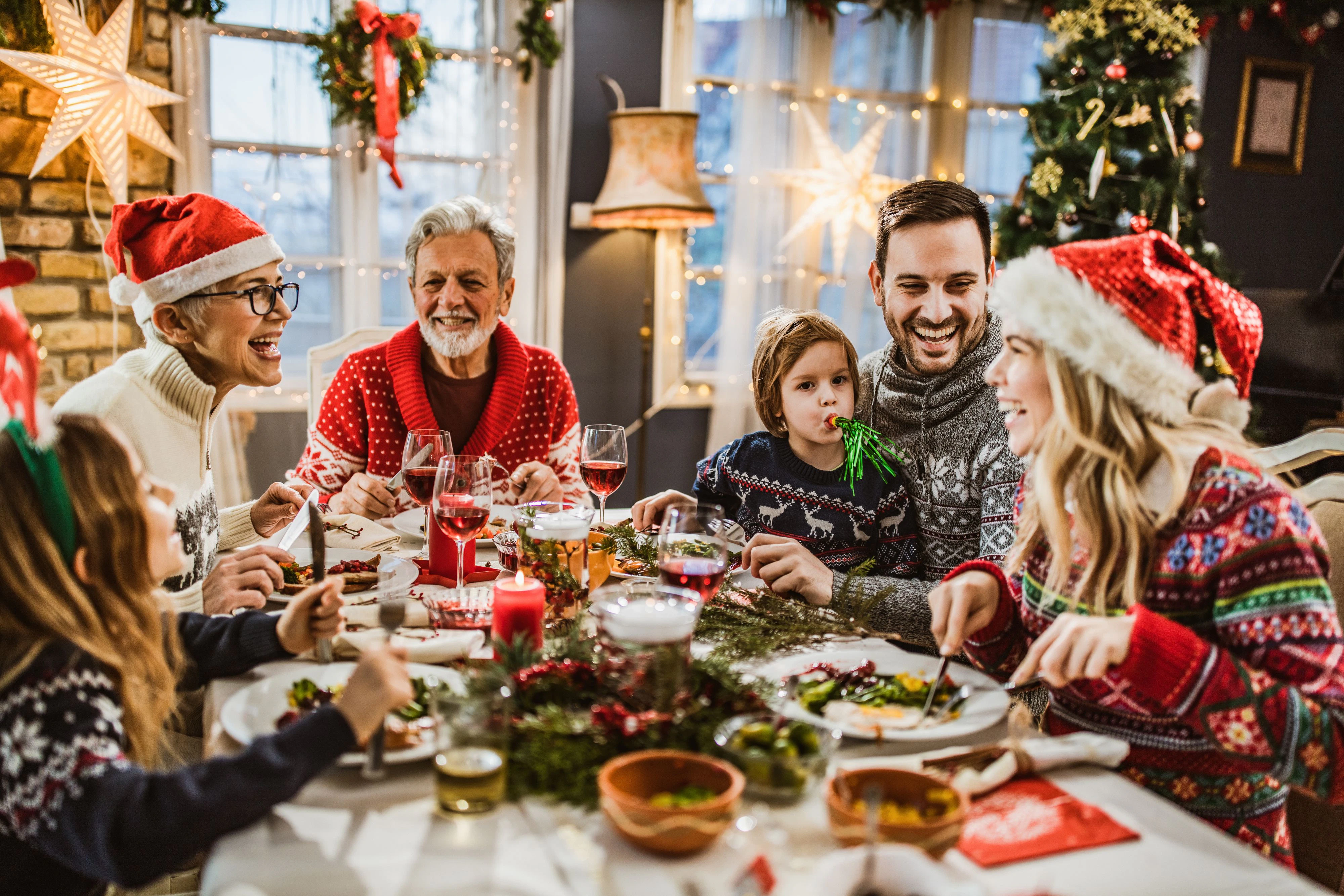 Happy multi-generation family talking while having New Year's meal at dining table.