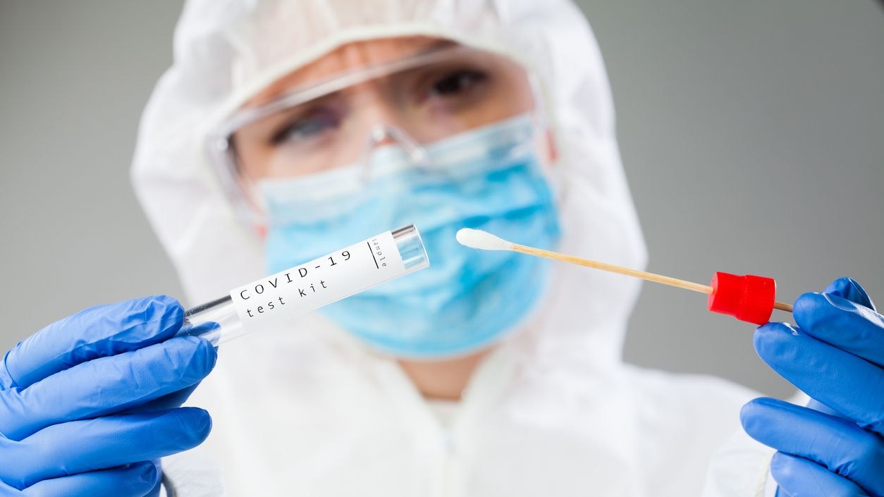 Medical healthcare technologist holding COVID-19 swab collection kit, wearing white PPE protective suit mask gloves, test tube for taking OP NP patient specimen sample,PCR DNA testing protocol process