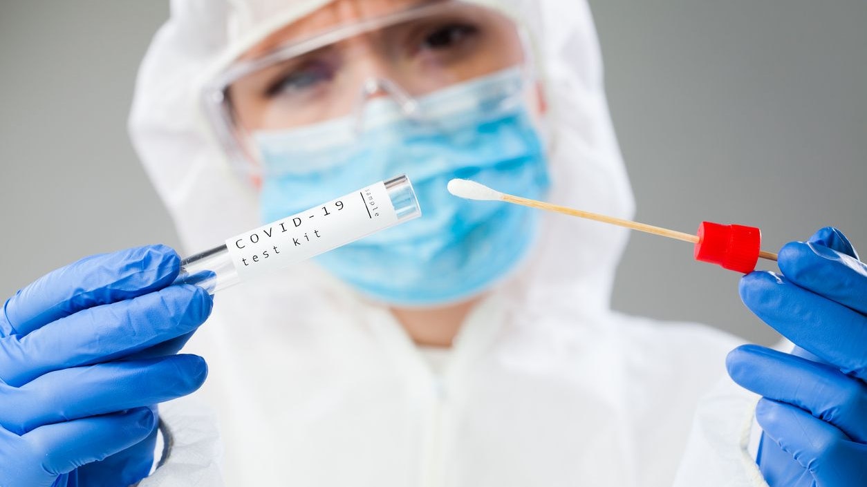 Medical healthcare technologist holding COVID-19 swab collection kit, wearing white PPE protective suit mask gloves, test tube for taking OP NP patient specimen sample,PCR DNA testing protocol process