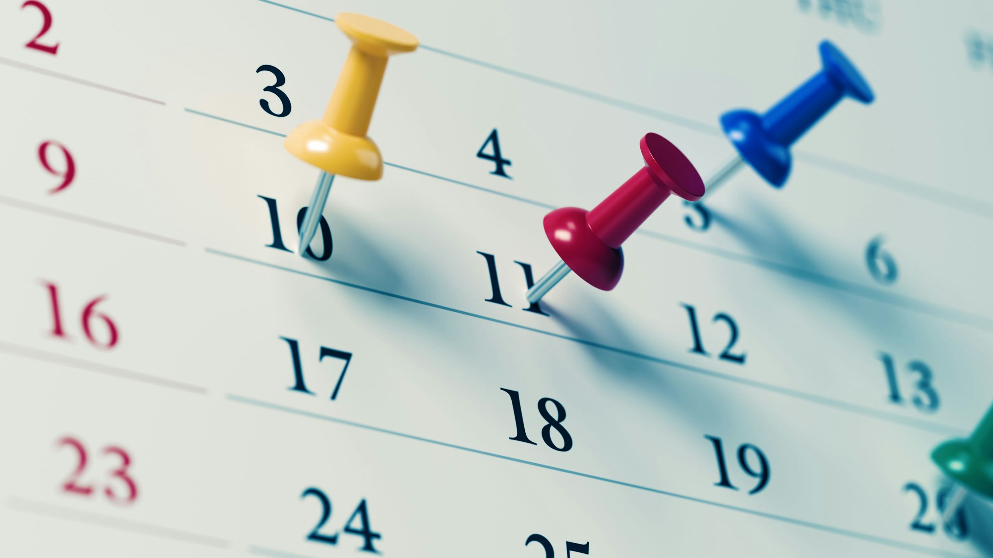 White calendar with colored push pins  reminding important dates. Calendar and reminder concept. Horizontal composition with copy space.
