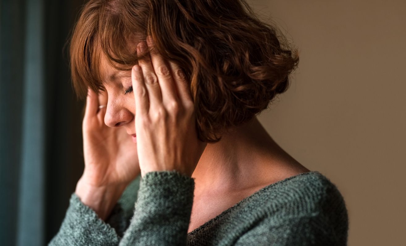 Close-up shot of a woman suffering from a headache and rubbing her temples  at home