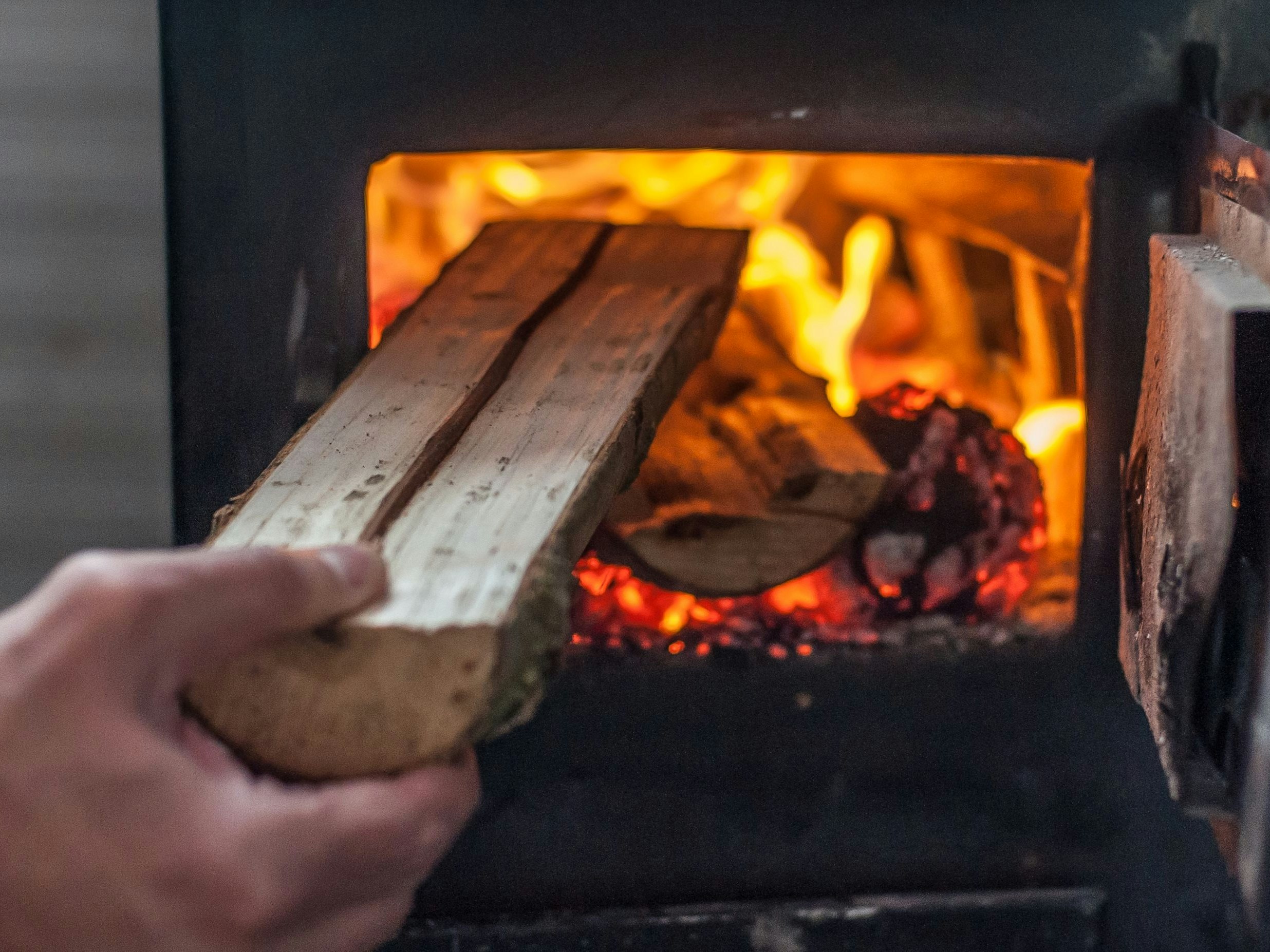 Man putting log to wood burning stove. Close up