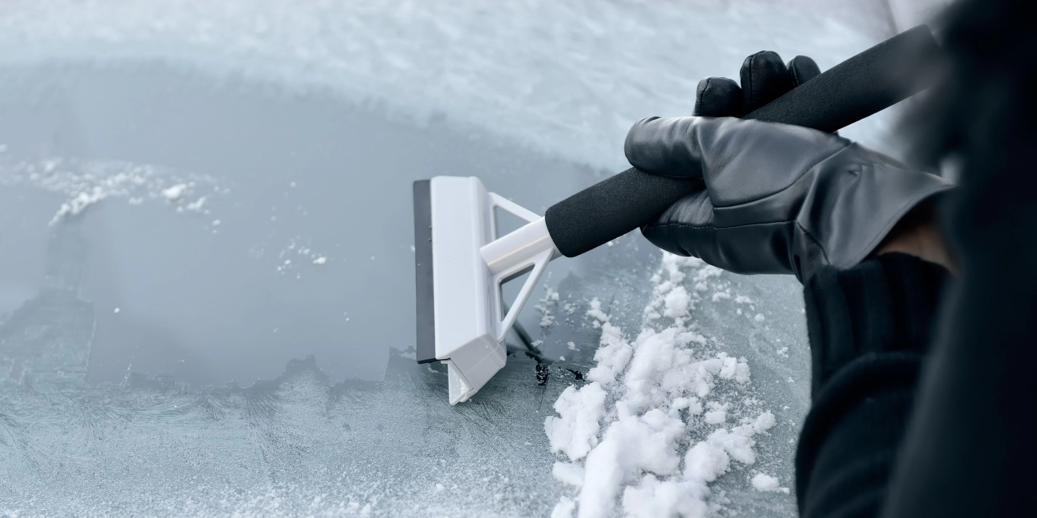 Winter Driving - Woman scraping ice from a windshield