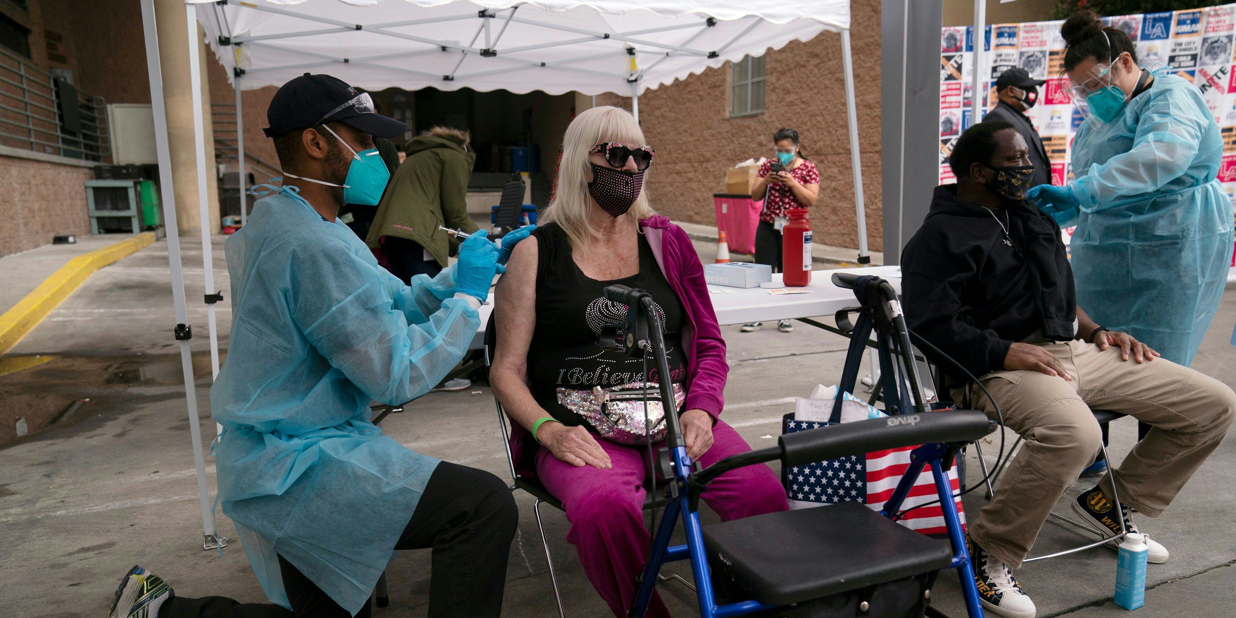 A nurse administers a COVID-19 vaccine to Connie Lach, 66, at a vaccination site set up in the parking lot of the Los Angeles Mission in the Skid Row area of Los Angeles.