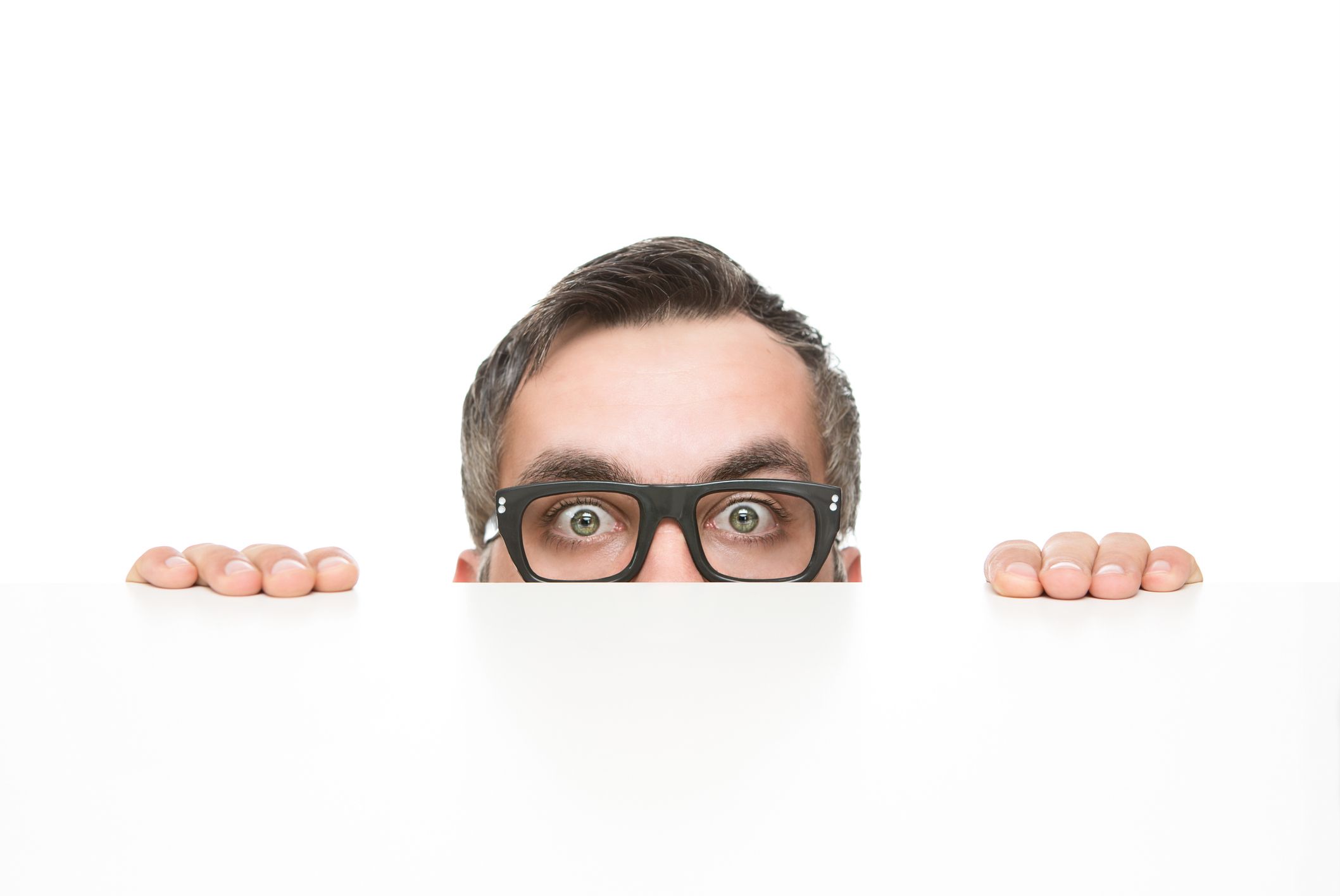 Funny nerd peeking from behind the desk isolated on white background with copy space