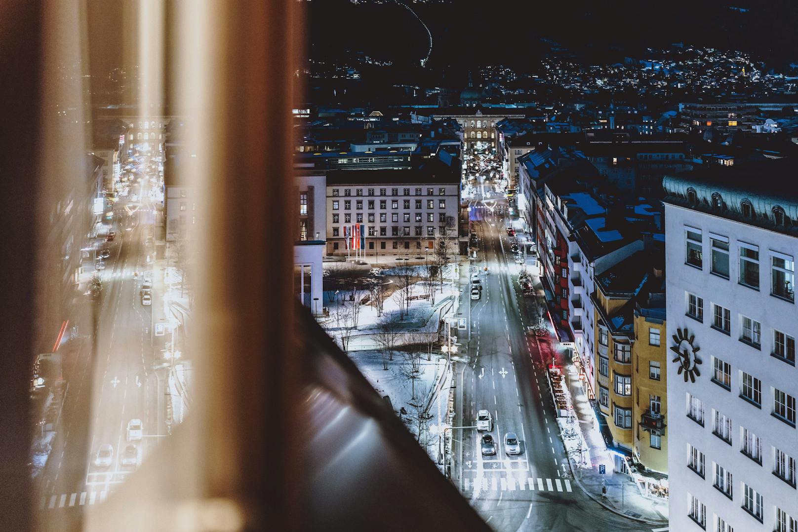 Blick aus einem Hotelzimmerfenster auf die beleuchteten Straßen der Tiroler Landeshauptstadt Innsbruck