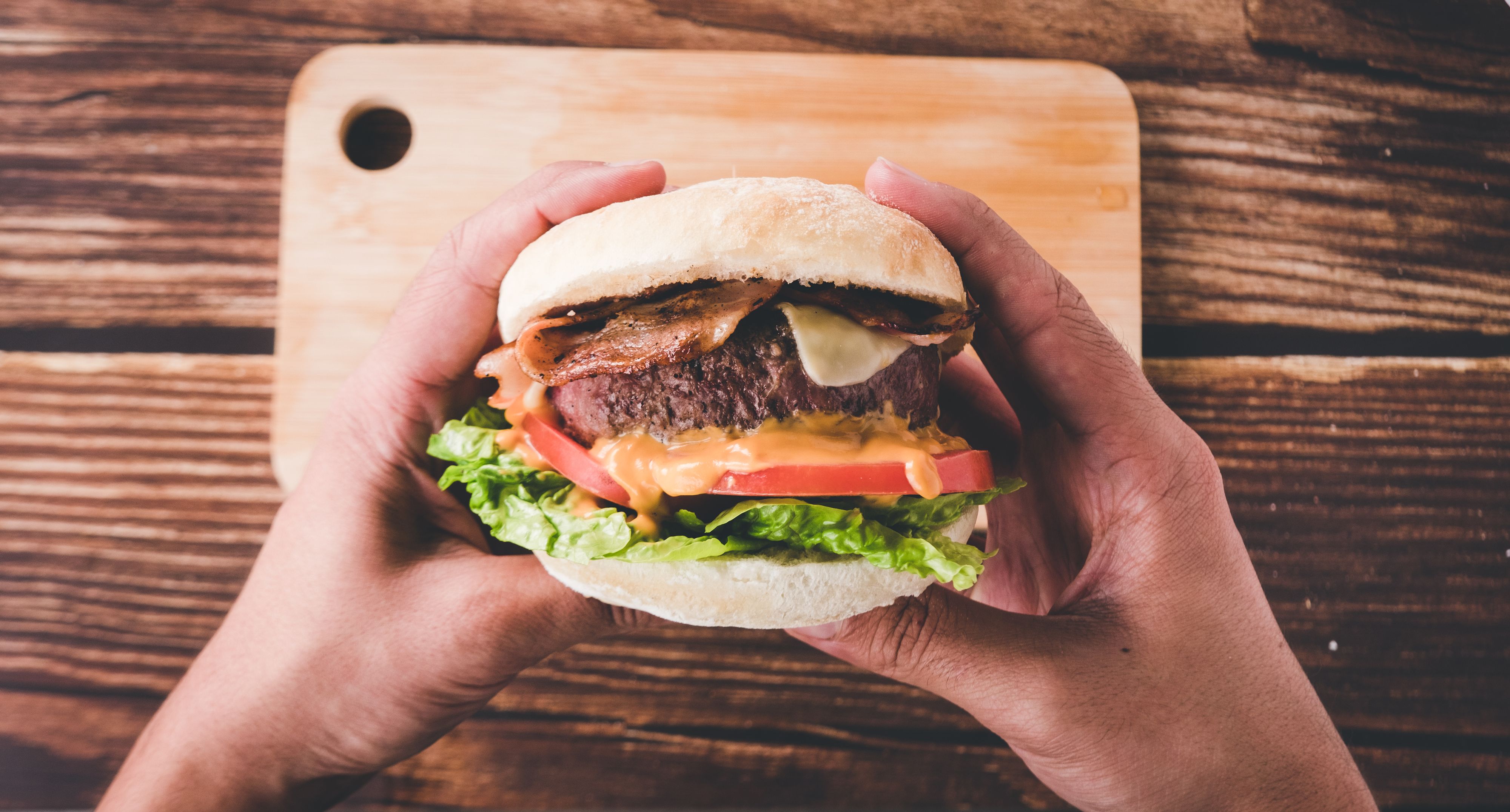 Hands holding a ready-to-eat hamburger at restaurant