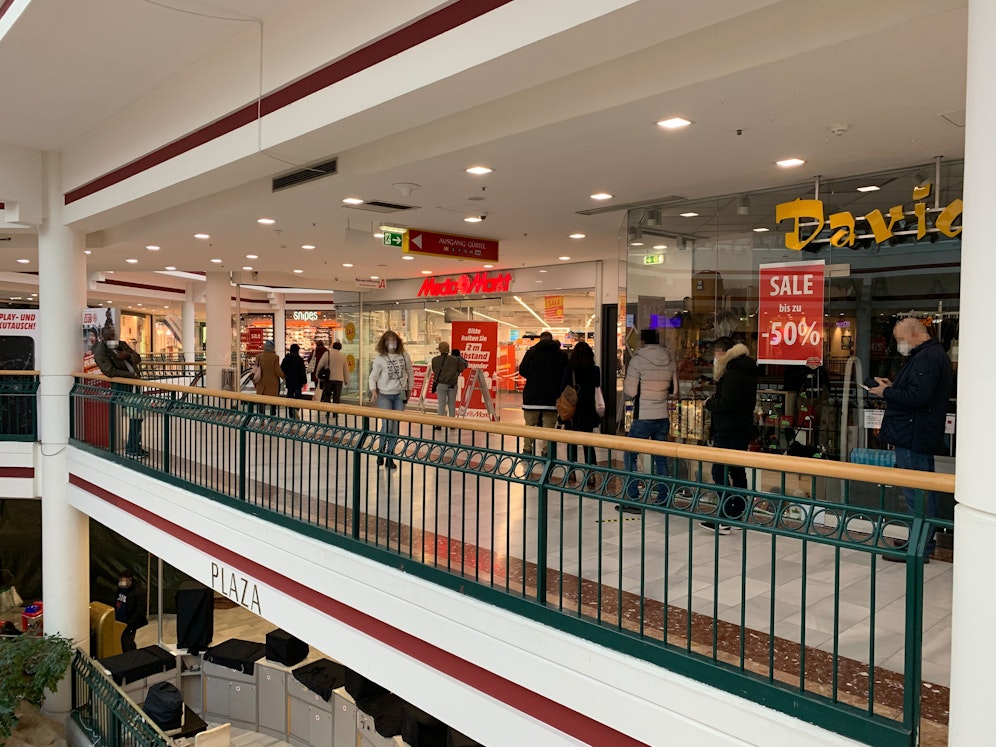 Vor dem Elektrohandelt warten mehrere Käufer auf ihre Produkte.