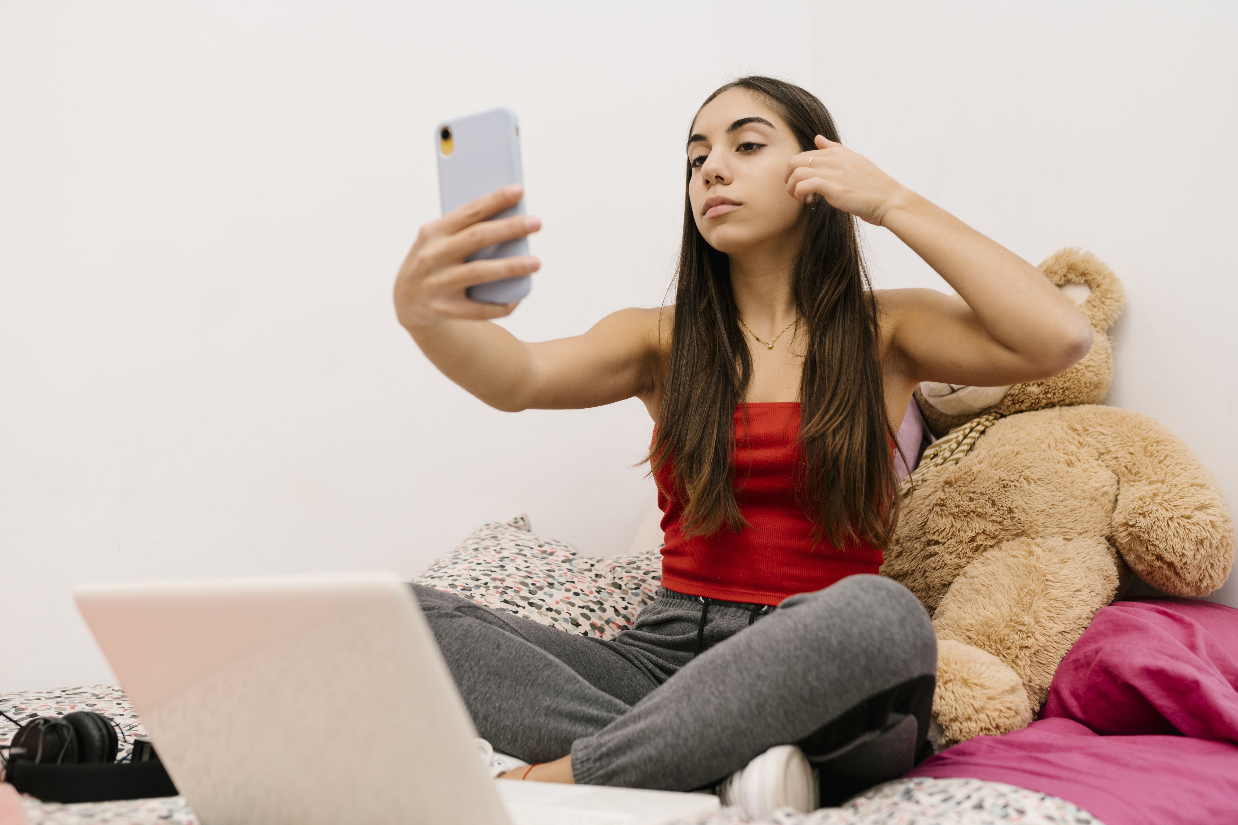 Download von www.picturedesk.com am 08.02.2021 (12:41).  Teenage girl sitting with hand in hair while using mobile phone sitting at home - 20201201_PD12158 - Rechteinfo: Royalty Free (RF) Model Released