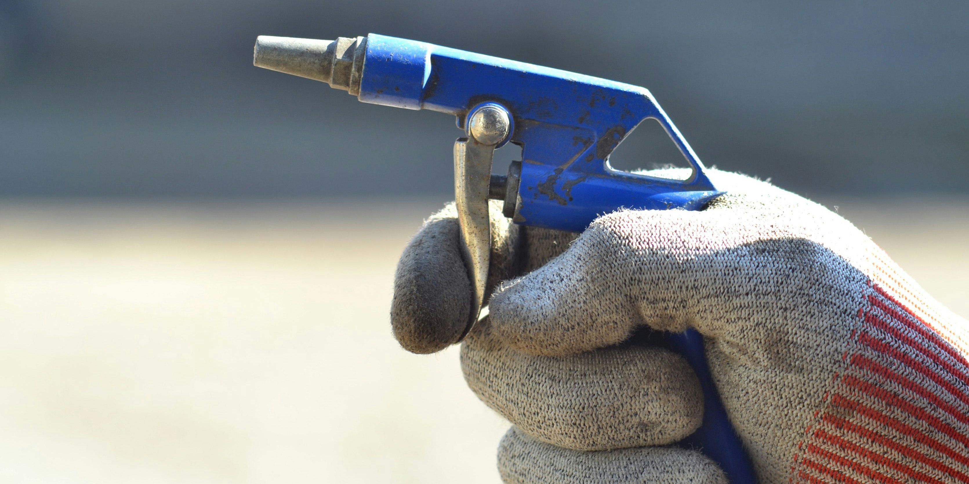 Druckluftpistole in der Hand eines Arbeiters. Symbolbild