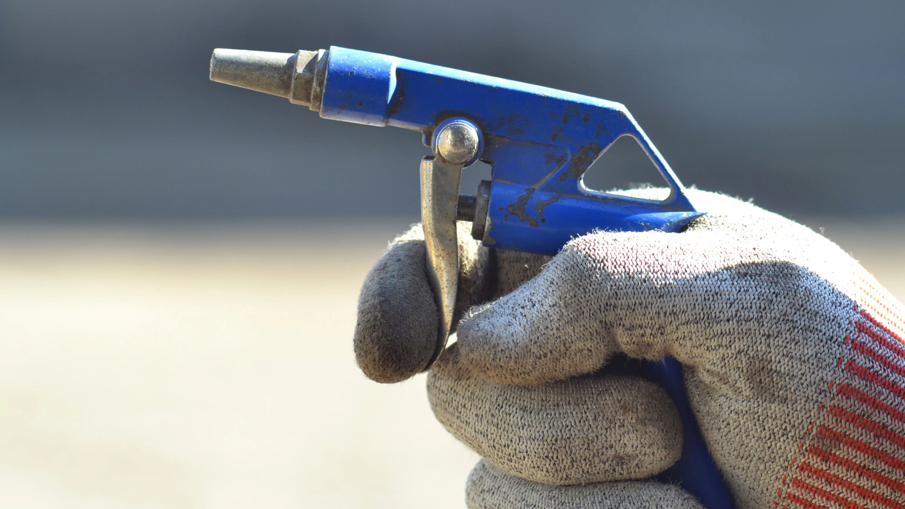 Druckluftpistole in der Hand eines Arbeiters. Symbolbild