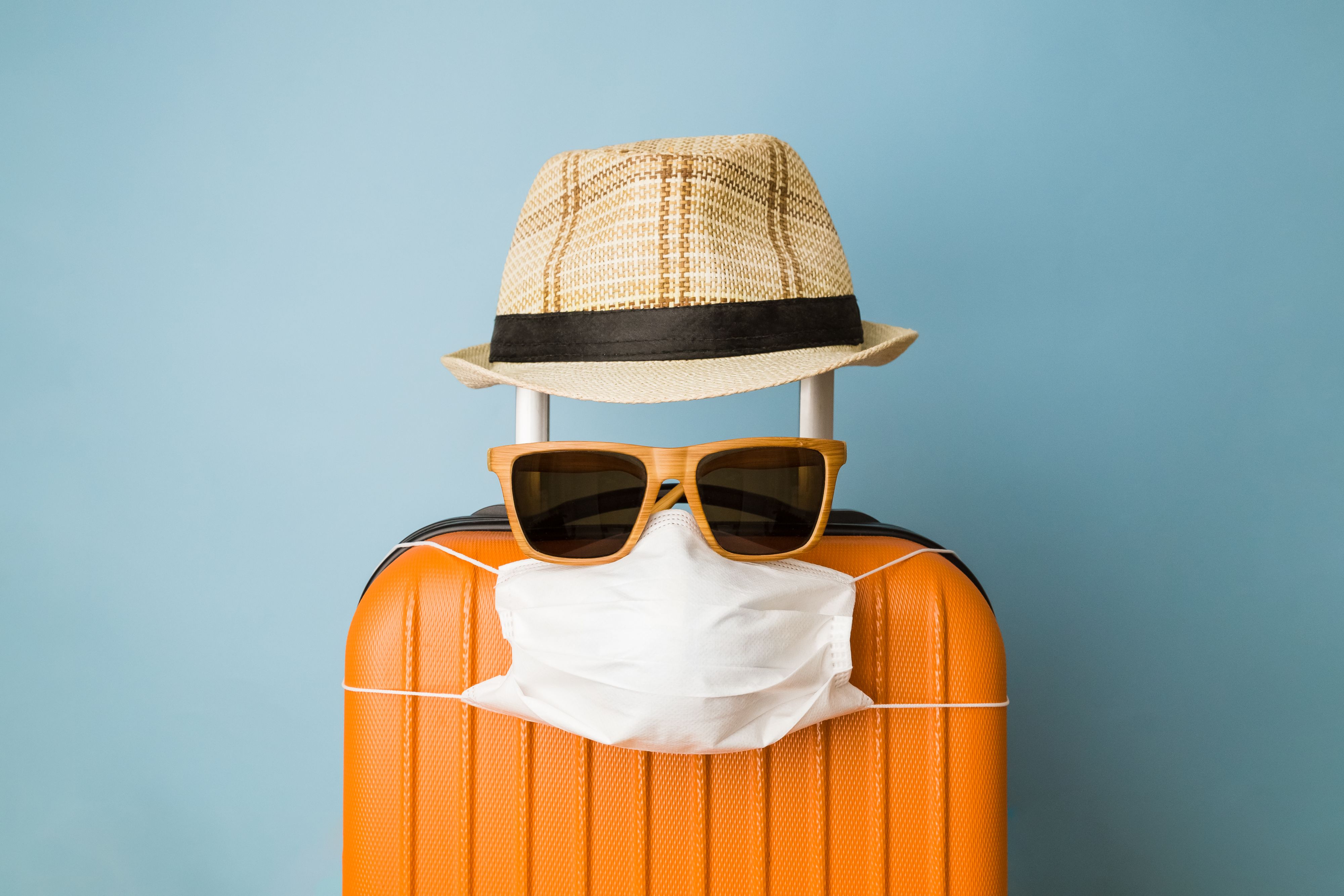 Travel restriction abstract made of tourist in form of of luggage with face mask, sunglasses and hat.