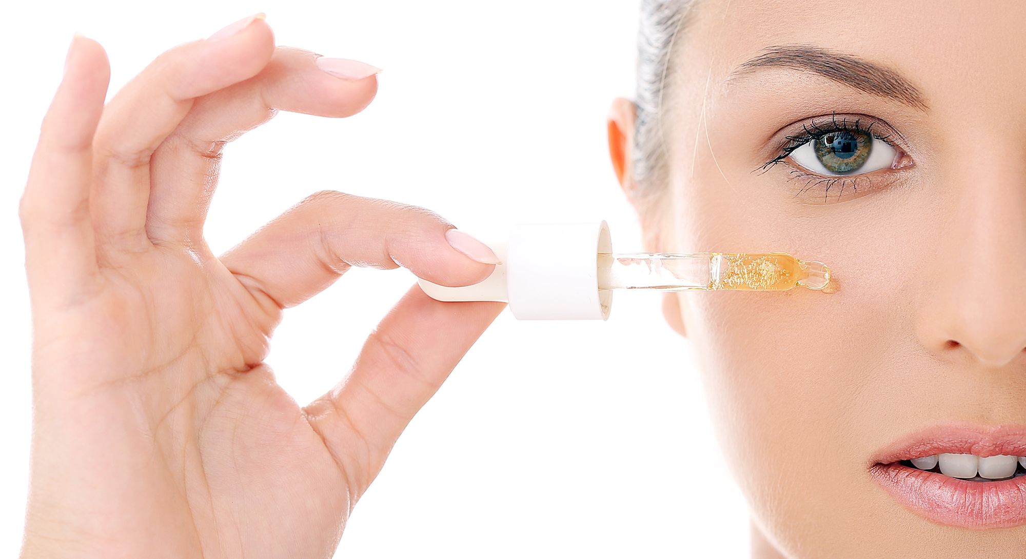 Portrait of a beautiful woman who is applying cosmetic oil over a white background