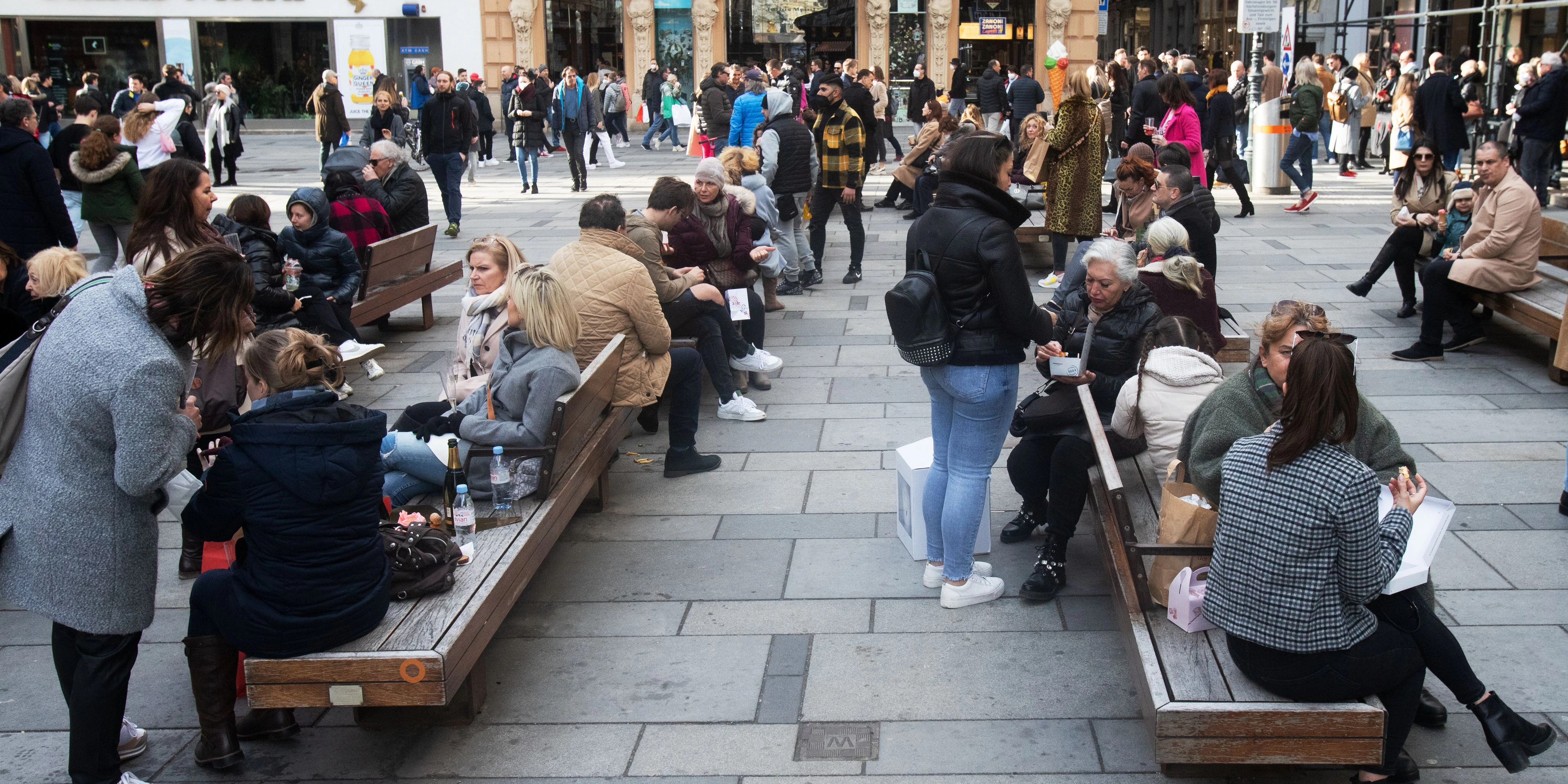 Menschen stehen bei sonnigem Wetter mit Getränken an der Kreuzung der Strasse Am Graben und der luxus Einkaufstrasse "Kohlmarkt" mit dem Michaeler Tor der Wiener Hofburg im Hintergrund in der wiener Innenstadt am Samstag, 13. März 2021. Trotz der Corona Virus (COVID - 19) tragen die wenigsten FFP 2 Schutzmasken. In Österreich ist das tragen der Schutzmasken im Geschäften verpflichtend, im freien soll ein 2 Meter Abstand eigehalten werden.