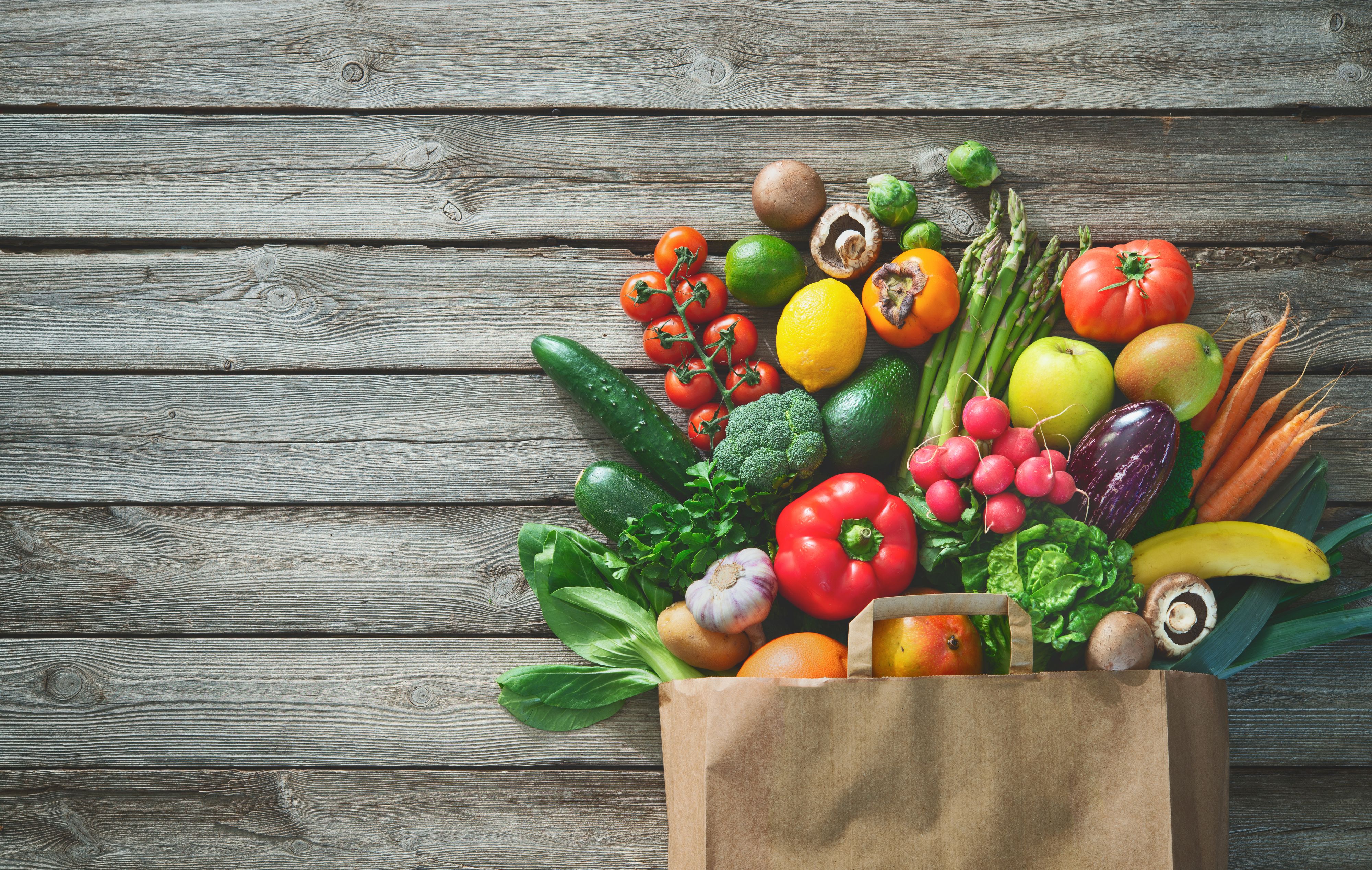 Healthy food selection. Shopping bag full of fresh vegetables and fruits. Flat lay food on table