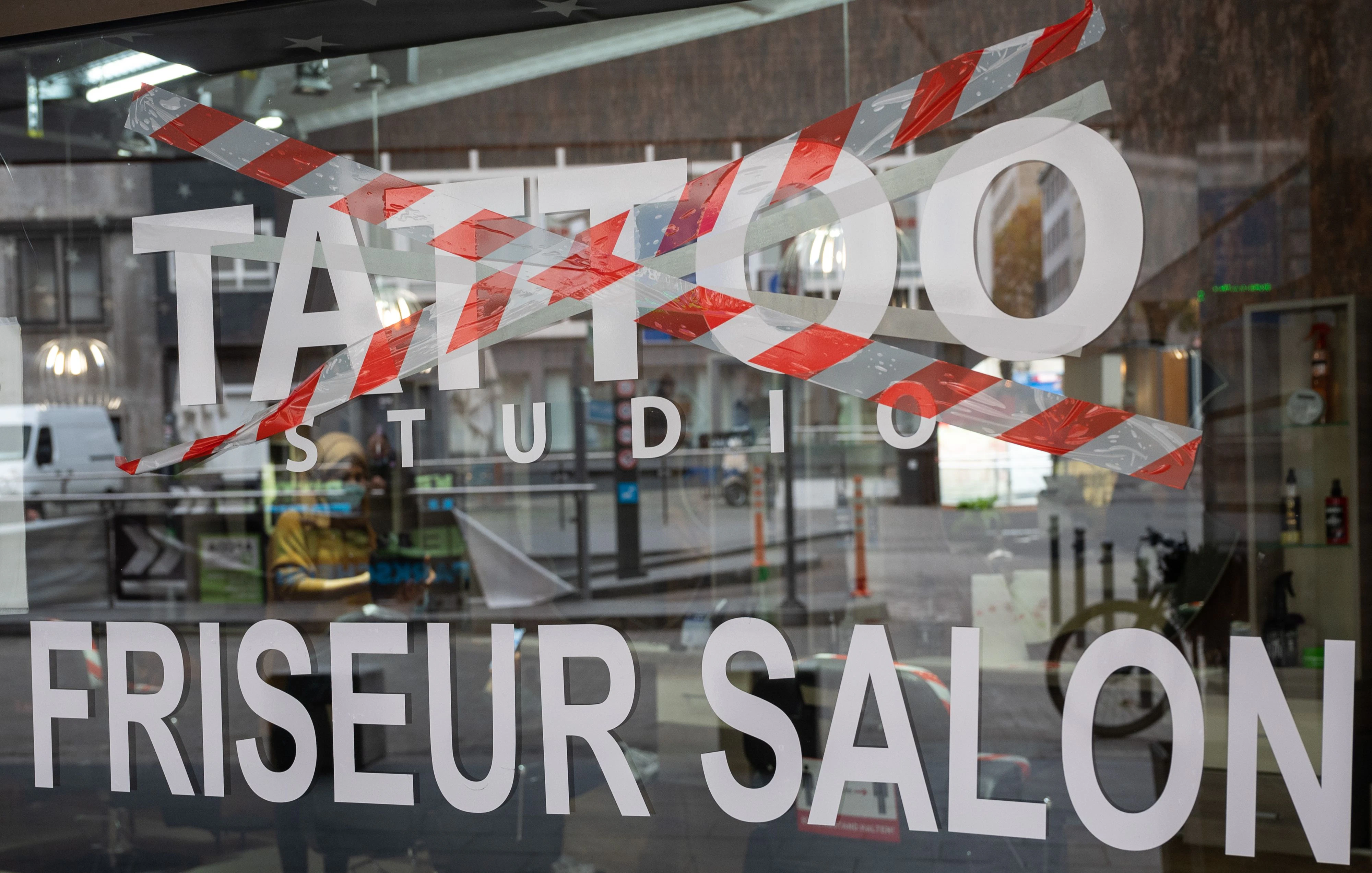 Download von www.picturedesk.com am 24.03.2021 (11:06).  04 November 2020, Baden-Wuerttemberg, Stuttgart: The word 'tattoo' is crossed out on the window of a beauty salon, while 'hairdresser's salon' is not crossed out. Since November 2, a partial lockdown, probably limited to November, has been in effect - hairdressers are still allowed to do their work. Tattoo and nail studios will have to remain closed, however. Photo: Sebastian Gollnow/dpa - 20201104_PD4027 - Rechteinfo: Rights Managed (RM)