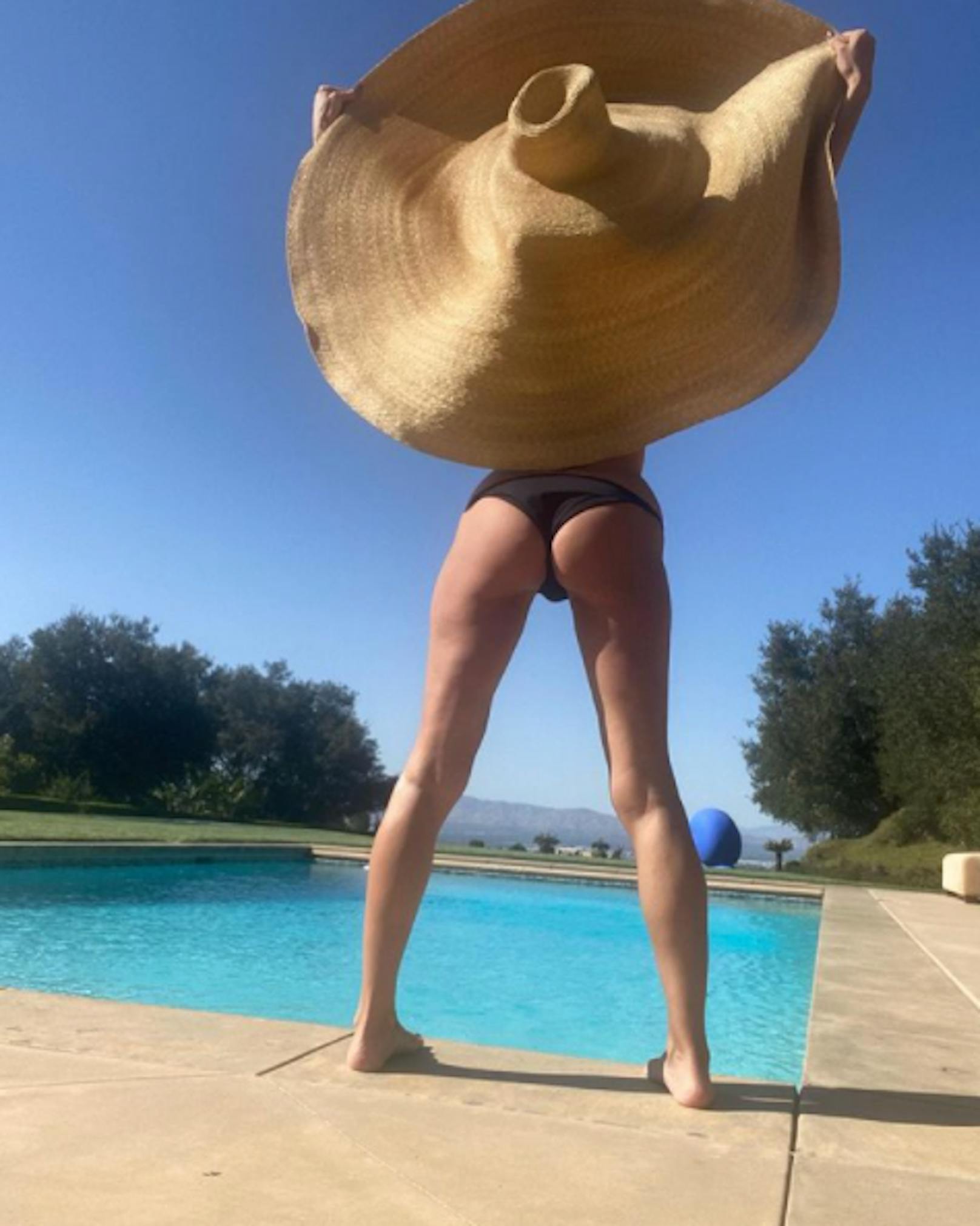 Wer hält hier diesen Riesen-Strohhut fest? Es ist die unverwüstliche Heidi Klum, die sich hier präsentiert.