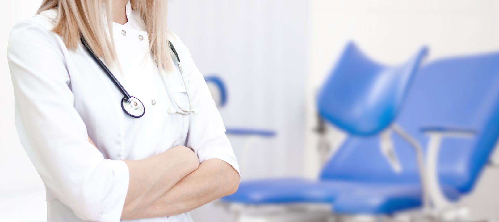 Gynecological banner with copyspace for text. Gynecologist doctor in white uniform in clinic hospital. cabinet with blue chair on background. Woman health and pregnancy concept