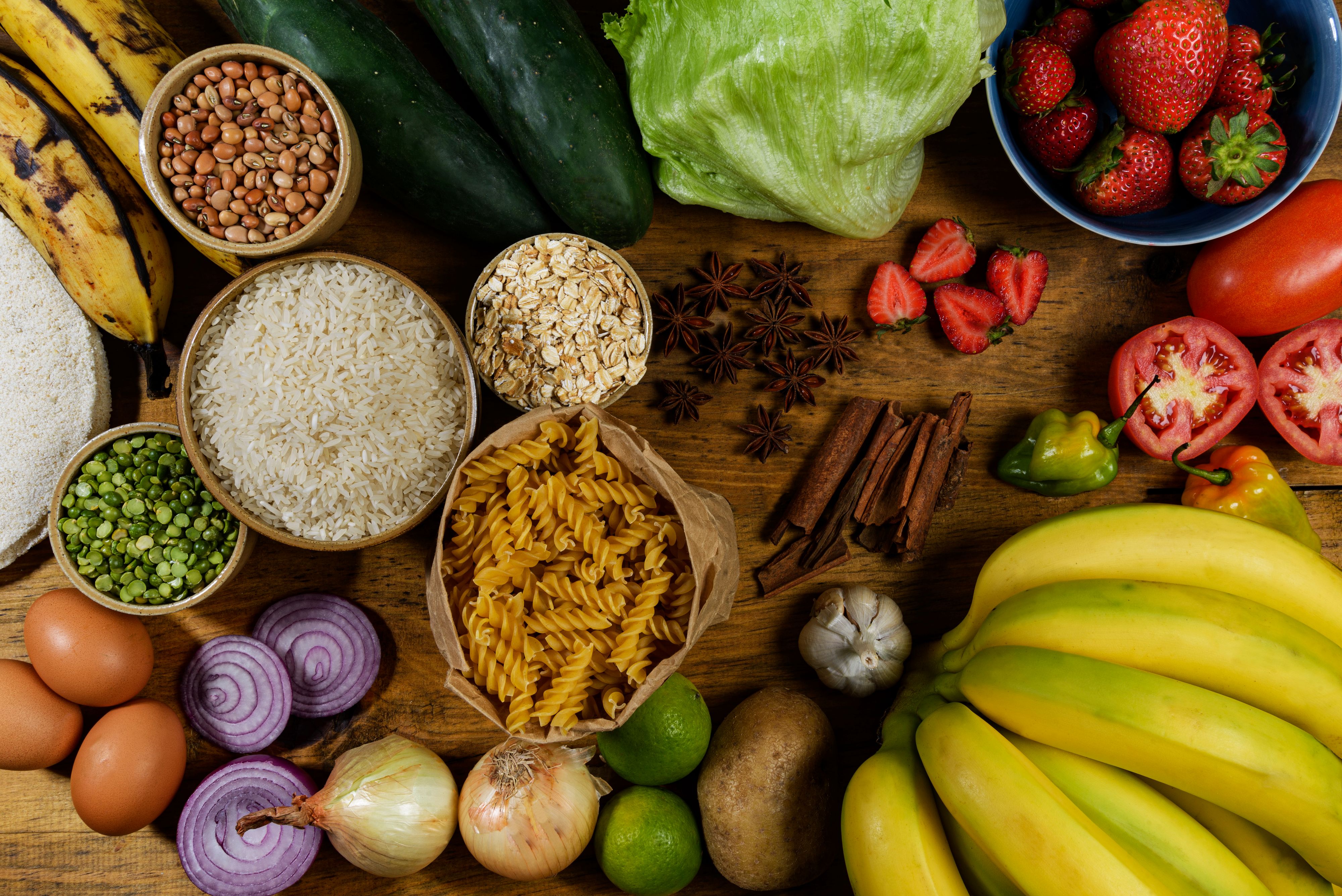 High angle view of healthy food ingredients with banana,garlic,potato,lemon,onion,spanish onion,eggs,green beans,cucumber,raw pasta,lettuce,oats,rice,strawberries,tomatos ,cinnamon sticks,star anise and chilli peppers. Images made in studio and processed in lightroom and photoshop.Camera used was a full frame of 24 megapixels camera.