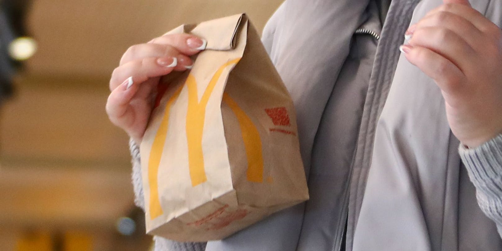Eine Kundin mit ihrer abgeholten Bestellung von McDonald's. Symbolfoto.