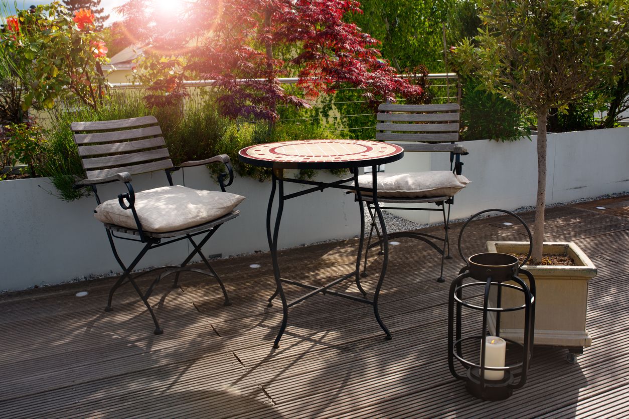 Garden terrace in summer with empty round table. Outdoor lifestyle with a candle. Background for decoration and space for text. Short depth of field.