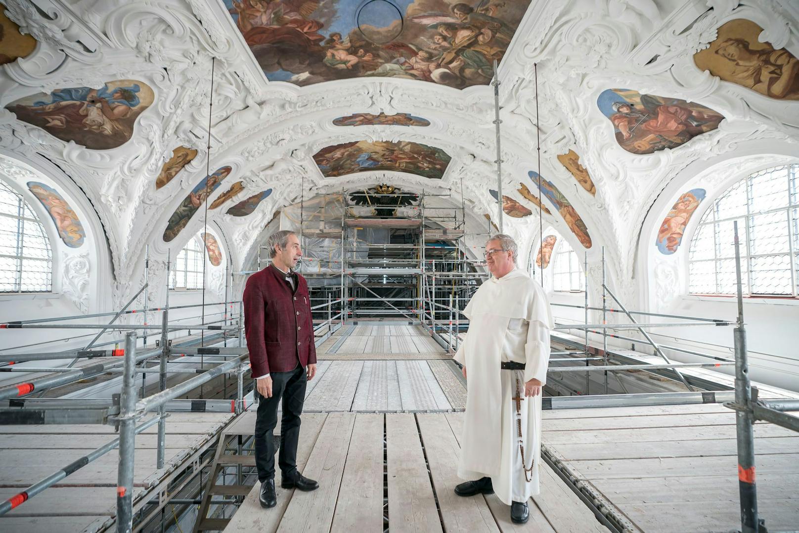 Dazu wurde im Innenraum der Kirche ein 26 Meter hohes Gerüst aufgebaut. "Von hier aus werden Schäden repariert und die prachtvollen Fresken restauriert", erklären der Architekt der Erzdiözese Wien Harald Gnilsen (l.) und Prior Günter Reitzi.