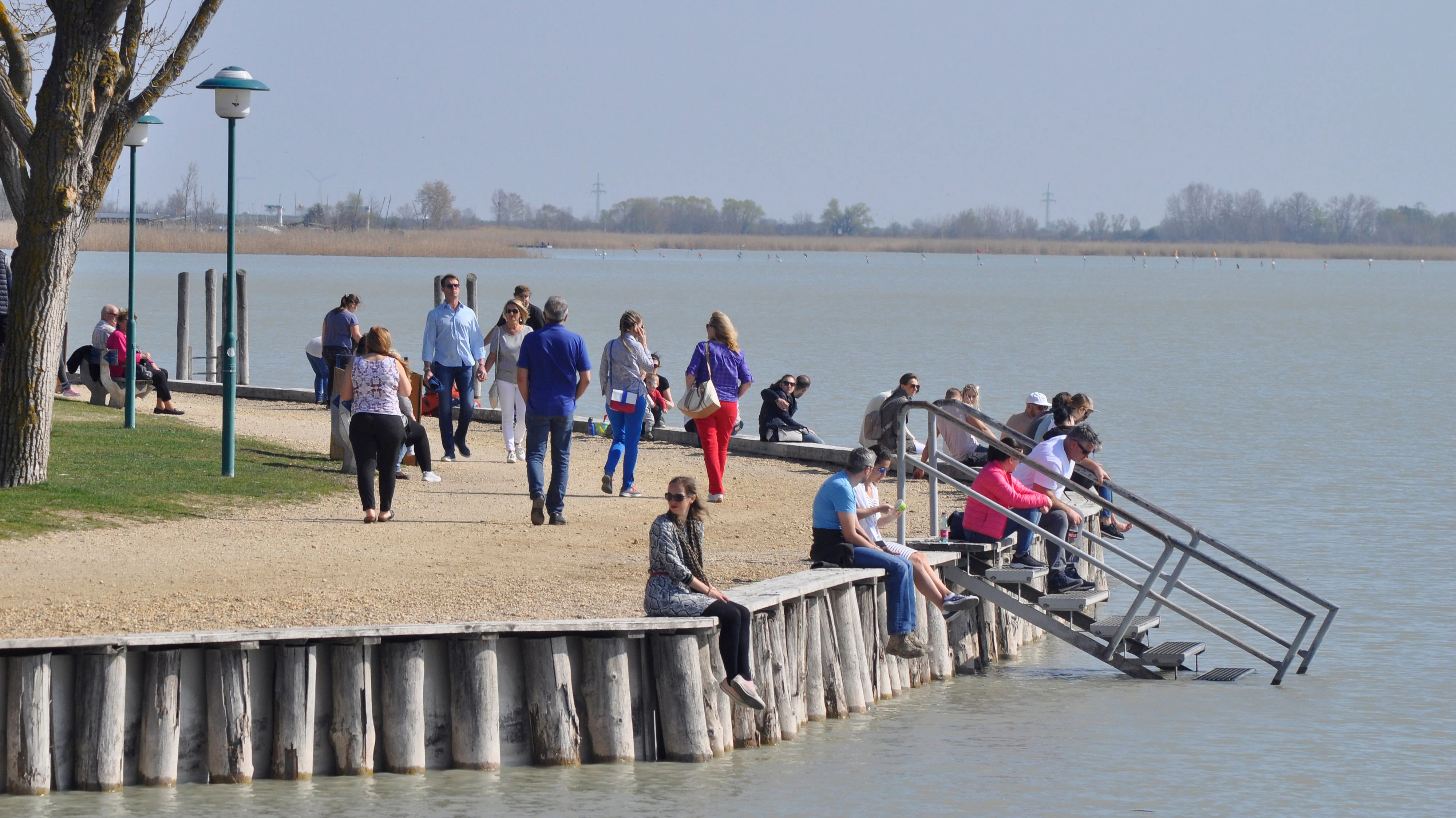 Menschen spazieren am Neusiedler See entlang.
