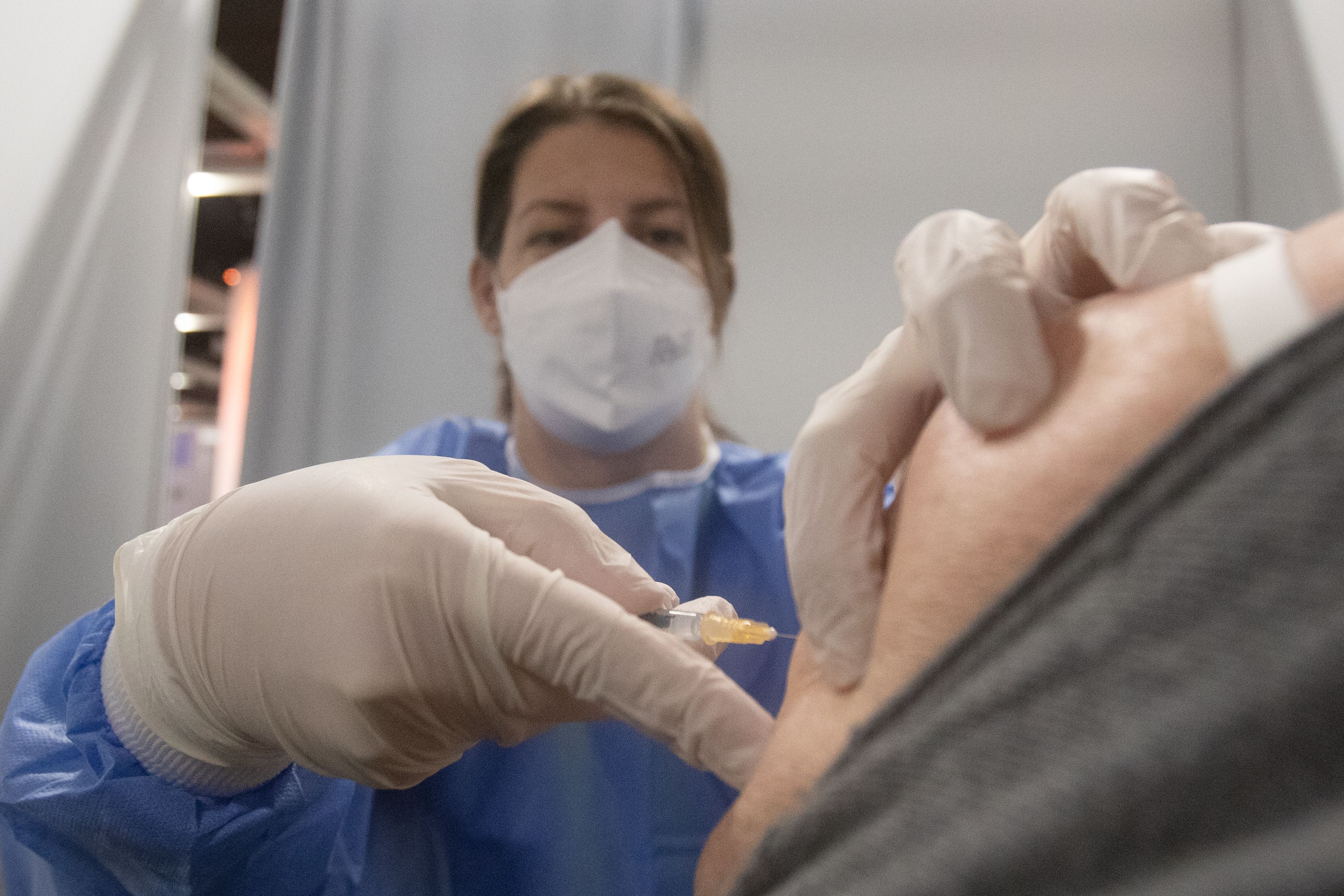 Eine Mittarbeiterin mit blauen Handschuhen impft mit einer Spritze einer ältere Frau in der Corona Virus (COVID-19) Impfstrasse im Austria Center Vienna (ACV) in Wien