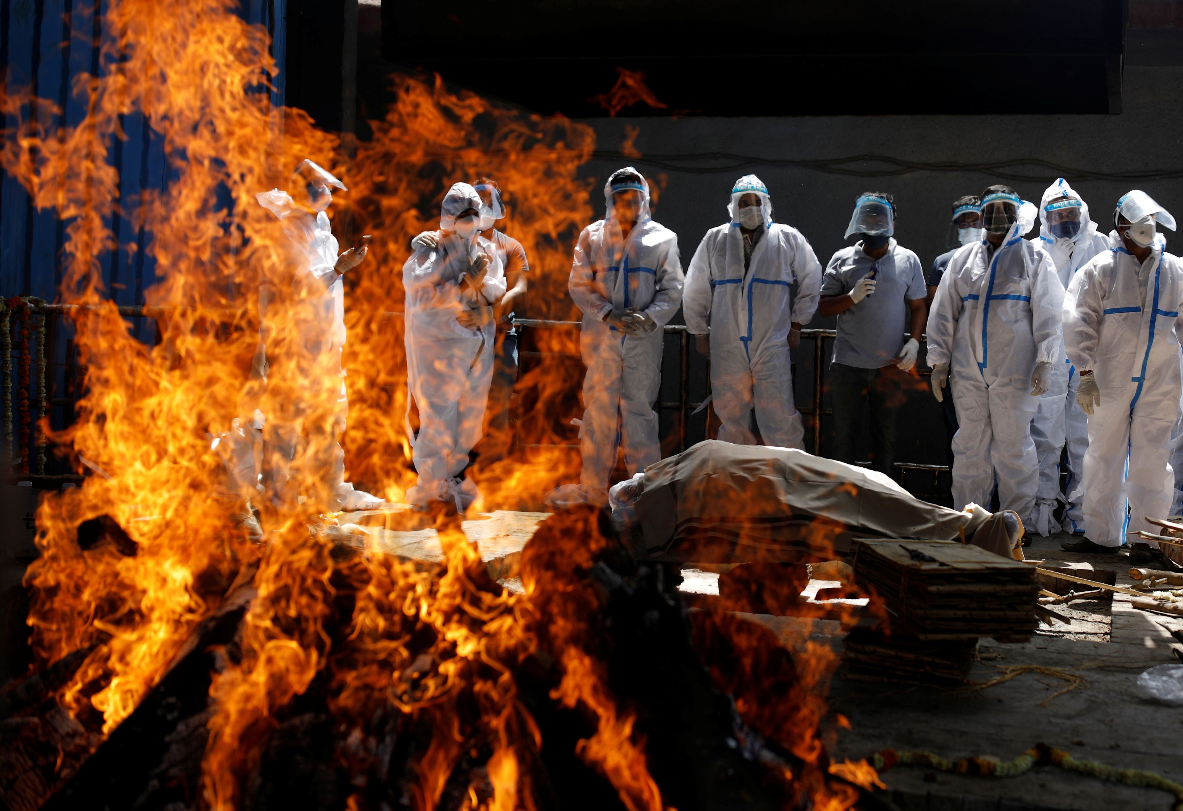 Relatives wearing personal protective equipment (PPE) attend the funeral of a man, who died from the coronavirus disease (COVID-19), at a crematorium in New Delhi, India April 21, 2021. REUTERS/Adnan Abidi