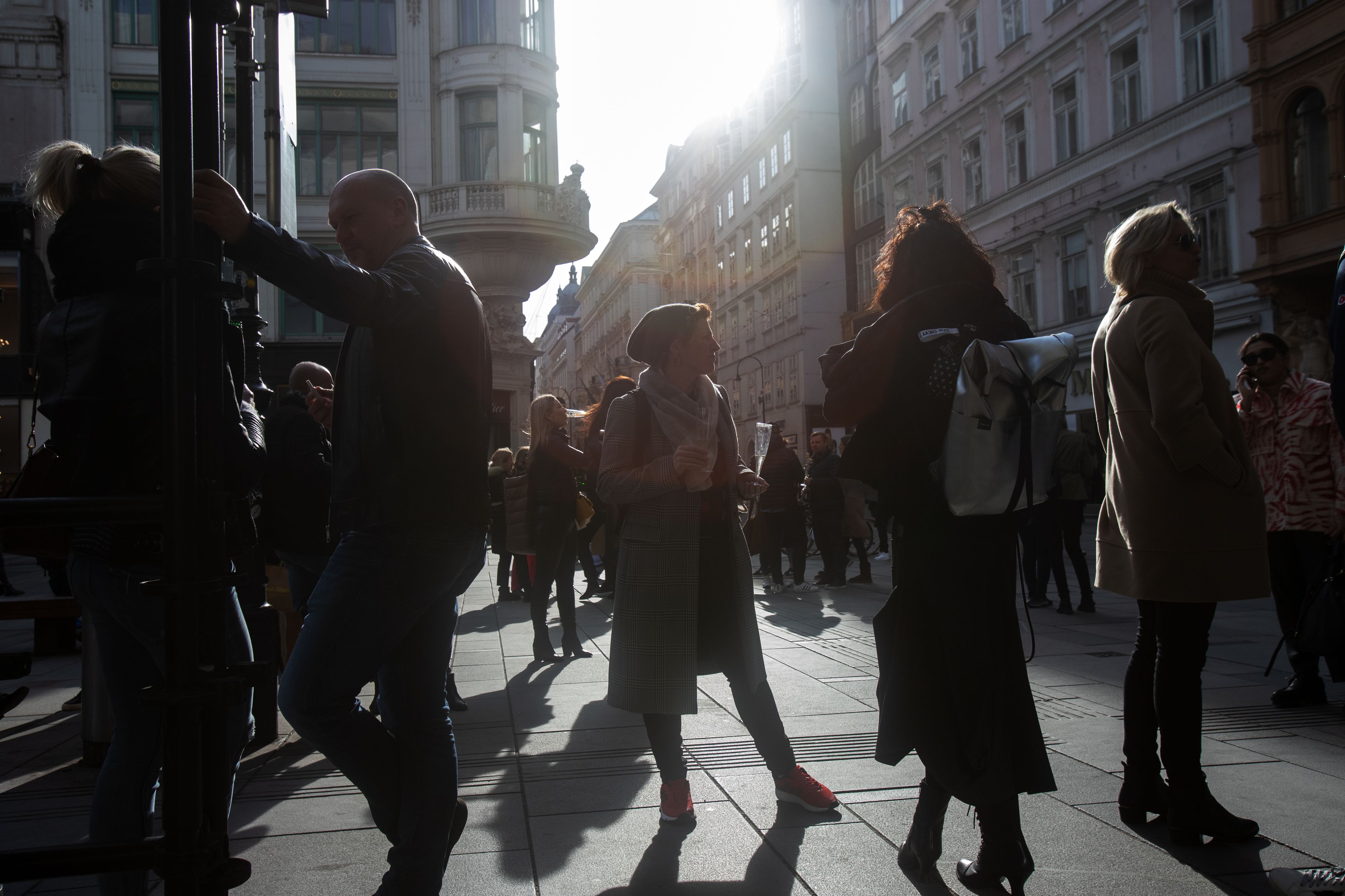 Passanten stehen bei sonnigem Wetter an einer Kreuzung in der Wiener Innenstadt. Symbolbild