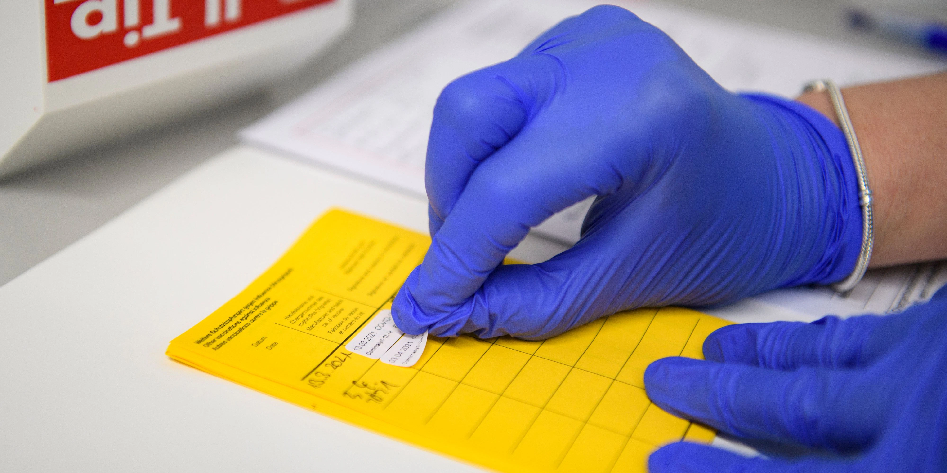 Download von www.picturedesk.com am 26.04.2021 (17:25).  03 April 2021, North Rhine-Westphalia, Velen: Information about the vaccination is entered in the vaccination certificate. People aged 60 and over can make an appointment for vaccination with the active substance from Astrazeneca in North Rhine-Westphalia from today. The first over-60s were even vaccinated today. Photo: Christopher Neundorf/dpa - 20210403_PD3230 - Rechteinfo: Rights Managed (RM)