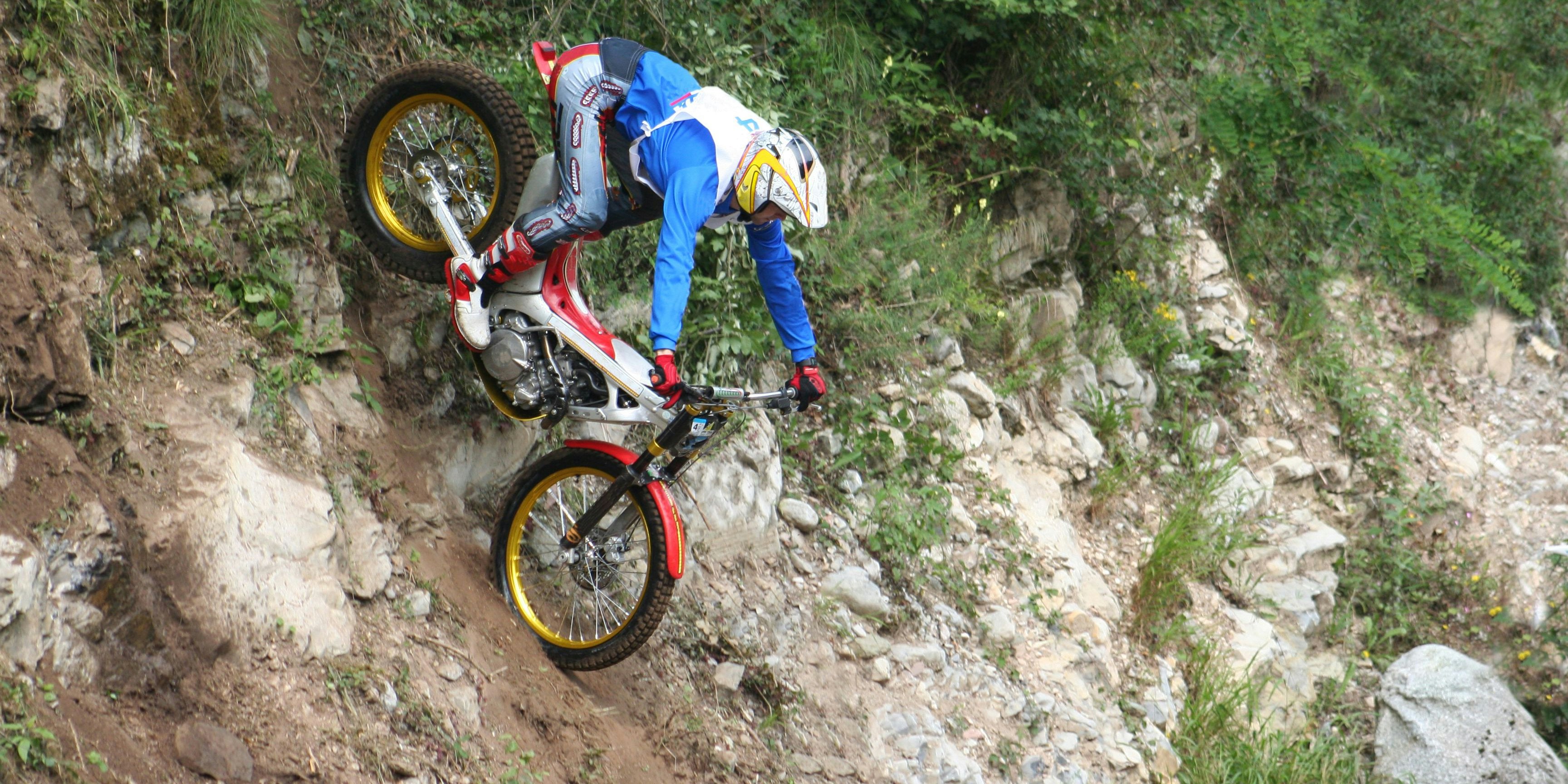 Trial motorcycle on rocks near a creek bed.