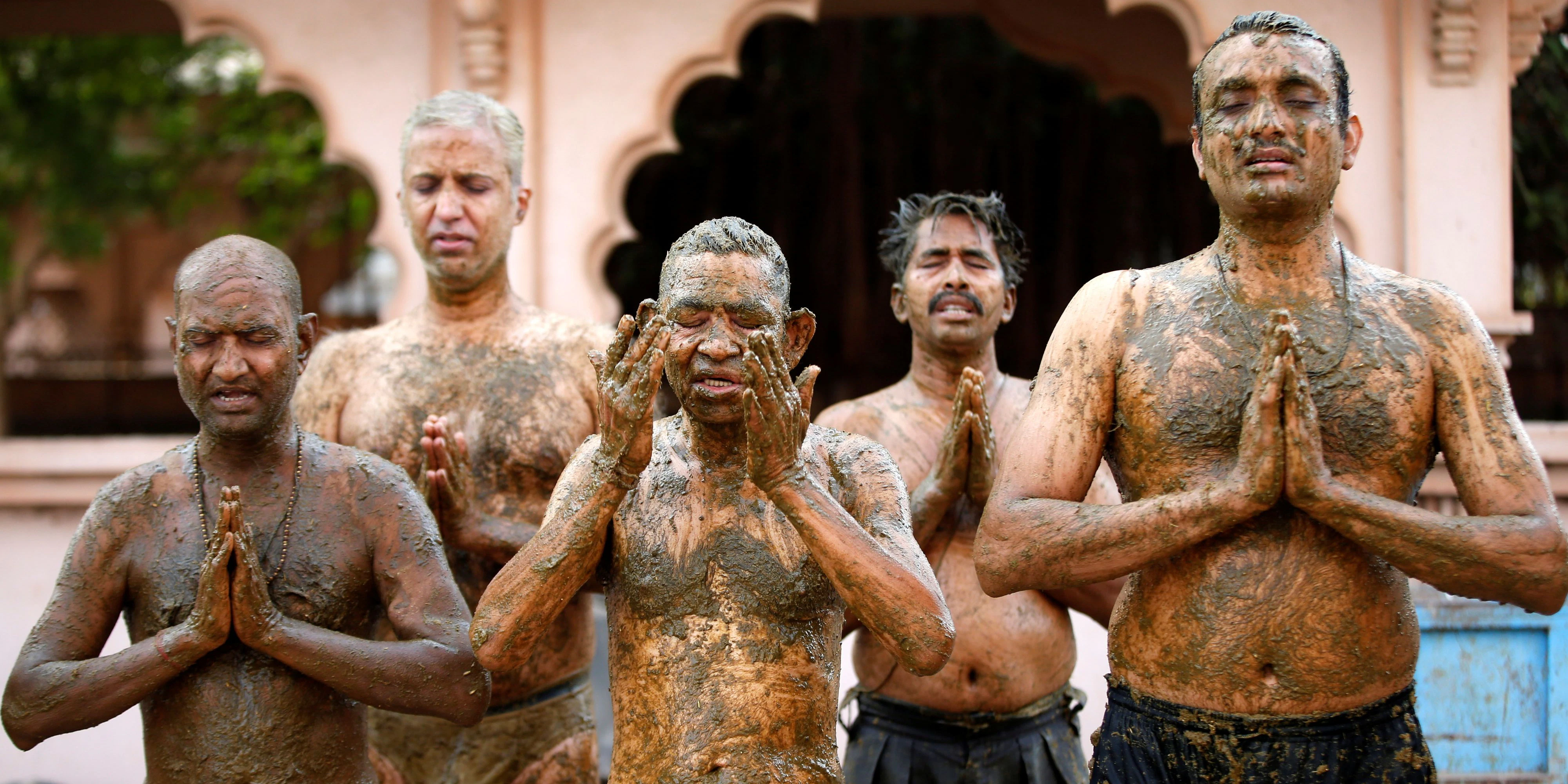 People pray after applying cow dung on their bodies during "cow dung therapy", believing it will boost their immunity to defend against the coronavirus disease (COVID-19) at the Shree Swaminarayan Gurukul Vishwavidya Pratishthanam Gaushala or cow shelter on the outskirts of Ahmedabad, India, May 9, 2021. Picture taken May 9, 2021. REUTERS/Amit Dave