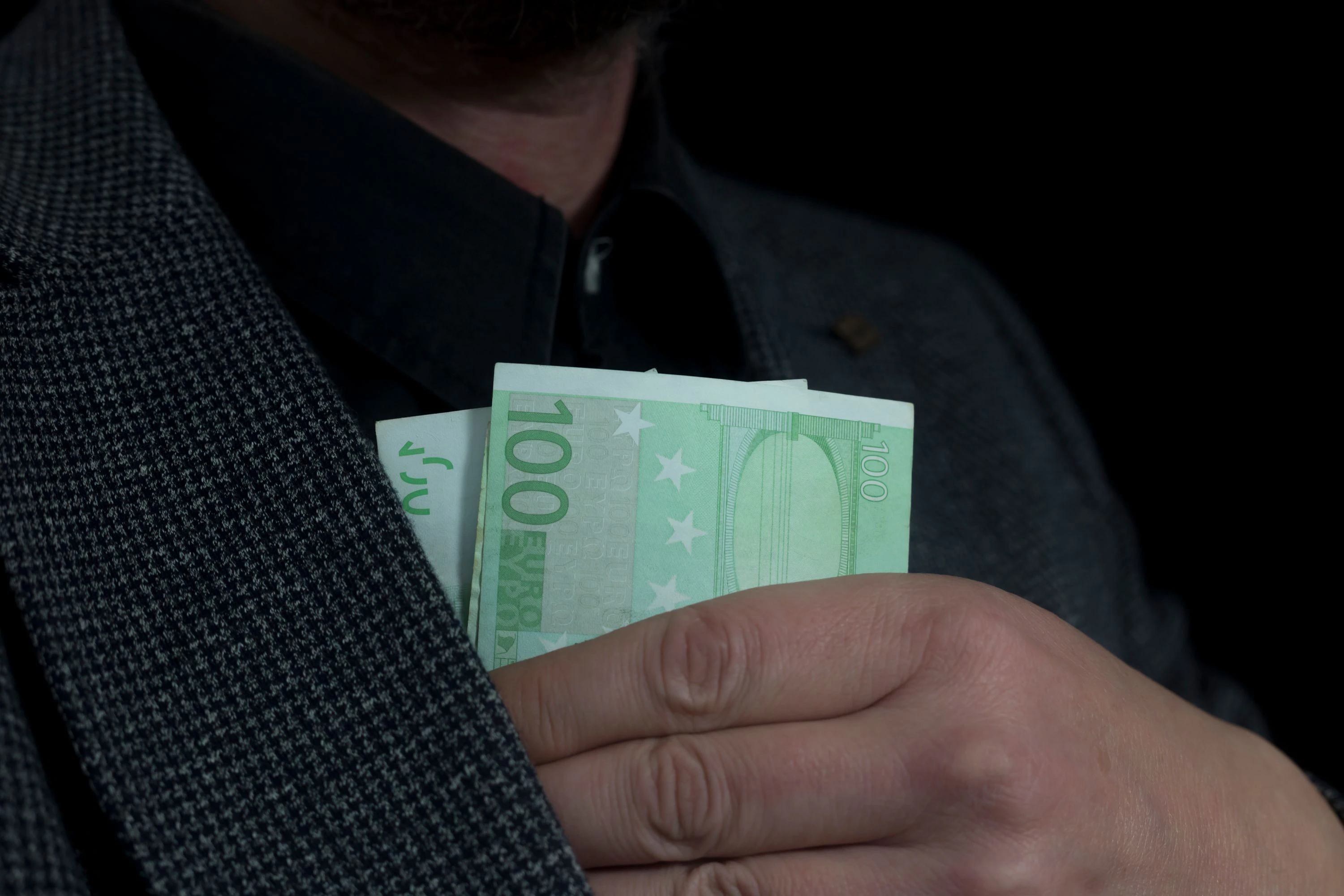 Ein Mann verstaut Bargeld in seinem Anzug.