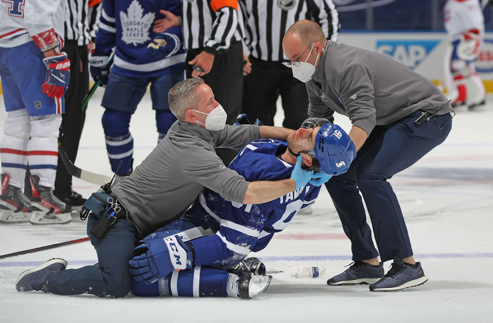 John Tavares kollabiert. Zwei Betreuer fangen seinen Sturz ab.