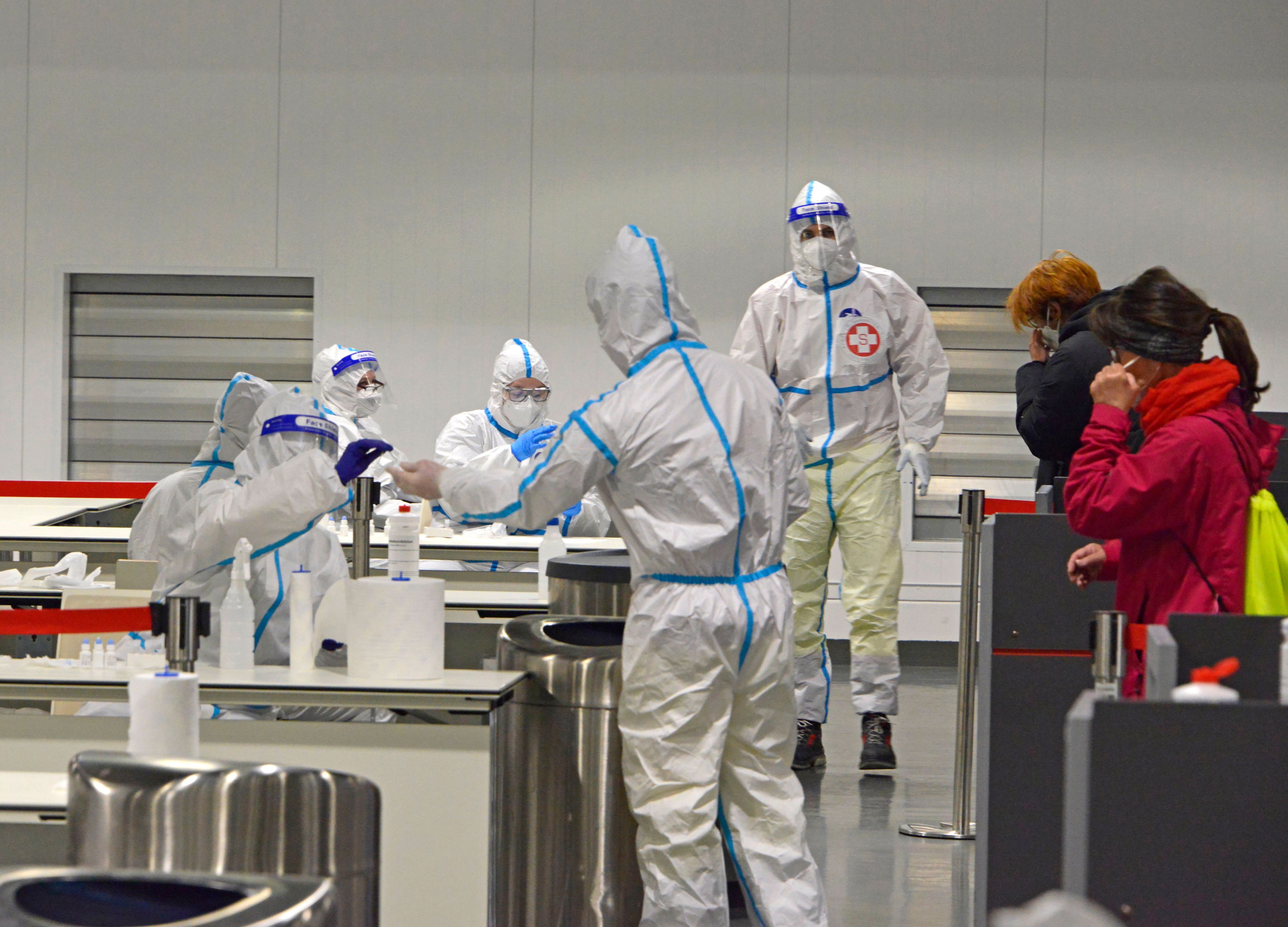 COVID-19 Antigen-Schnelltest im Austria Center Vienna. Leute lassen sich testen, Corona-Tester im Schutzanzug führen den Corona-Antigentest durch.