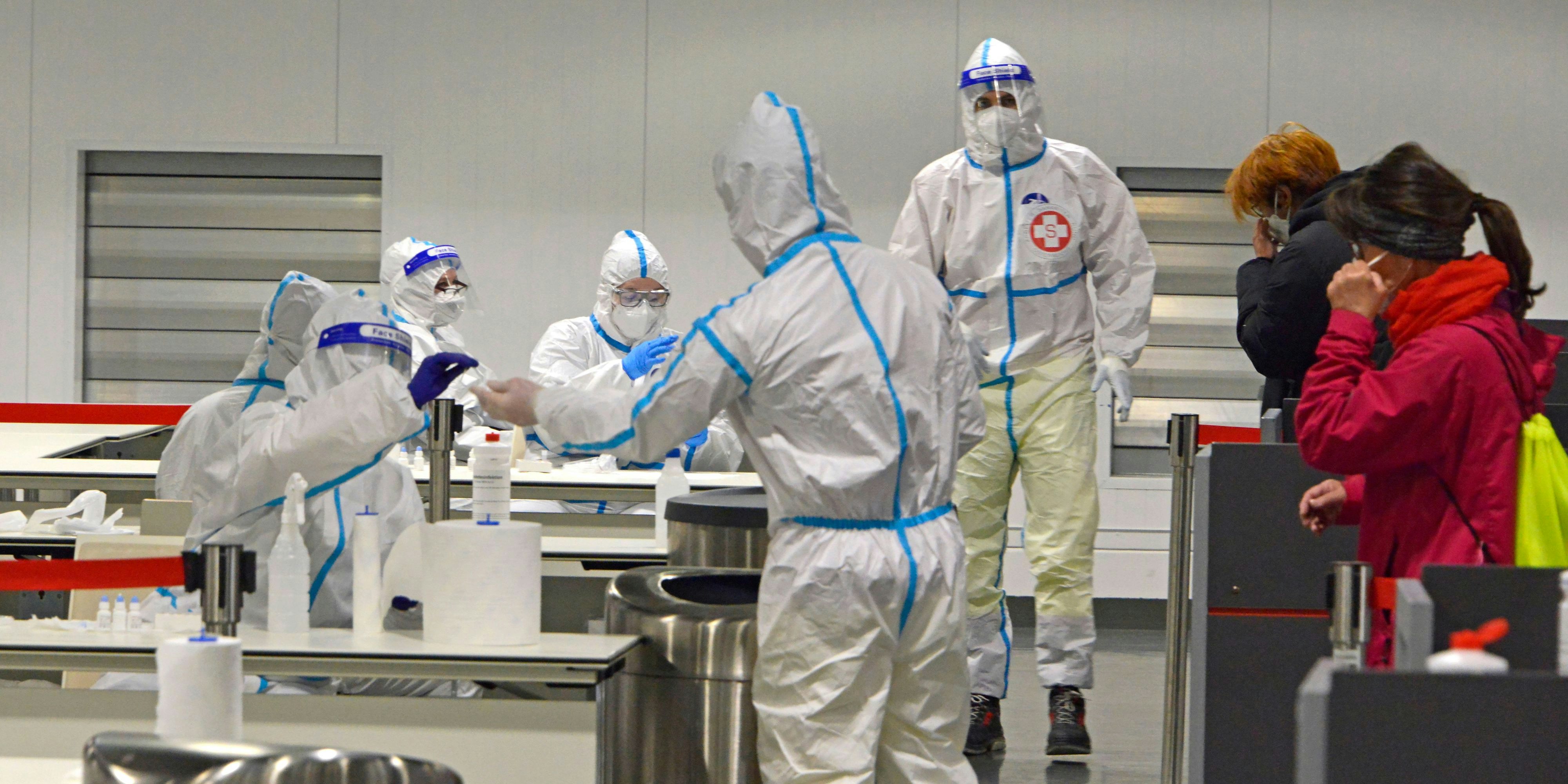 COVID-19 Antigen-Schnelltest im Austria Center Vienna. Leute lassen sich testen, Corona-Tester im Schutzanzug führen den Corona-Antigentest durch.
