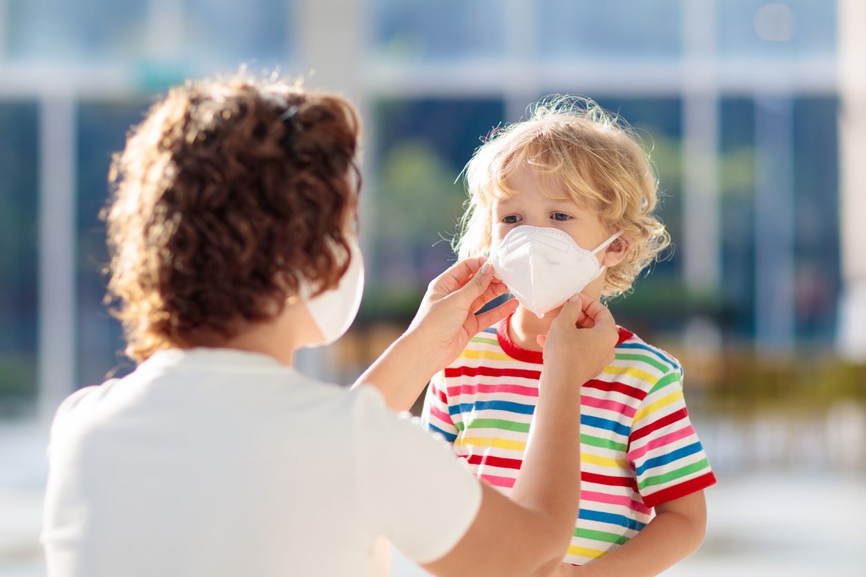 Family with kids in face mask in shopping mall or airport. Mother and child wear facemask during coronavirus and flu outbreak. Virus and illness protection, hand sanitizer in public crowded place.
