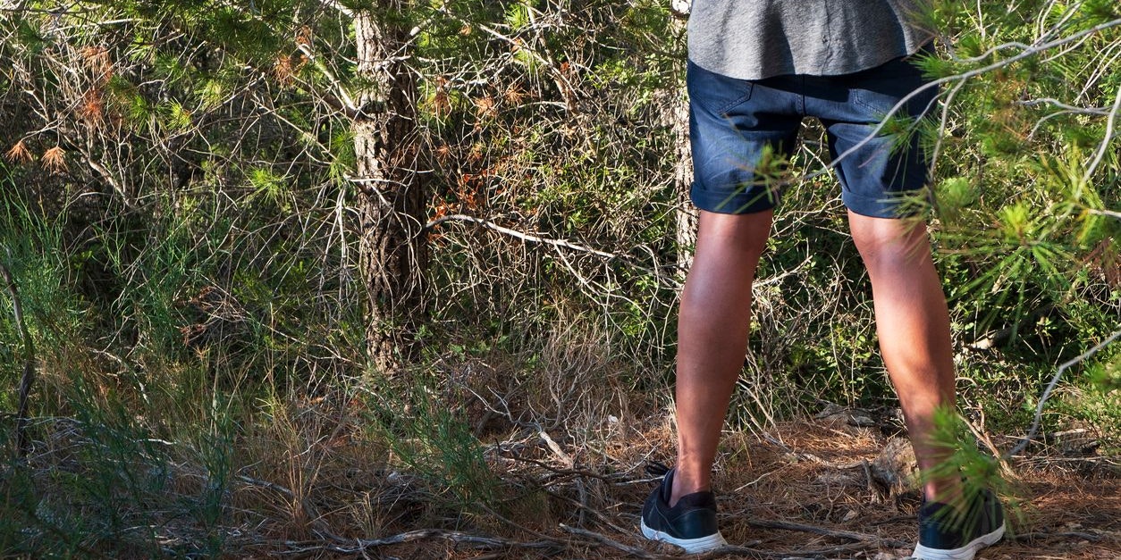 Ein Mann hat gegen einem Baum uriniert.