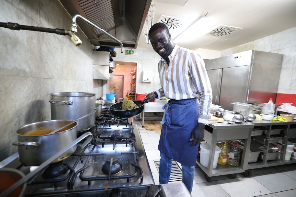 Am Herd schupft Khalifa Dampha seine Speisen mit einer großen Portion Geschmack und guter Laune.